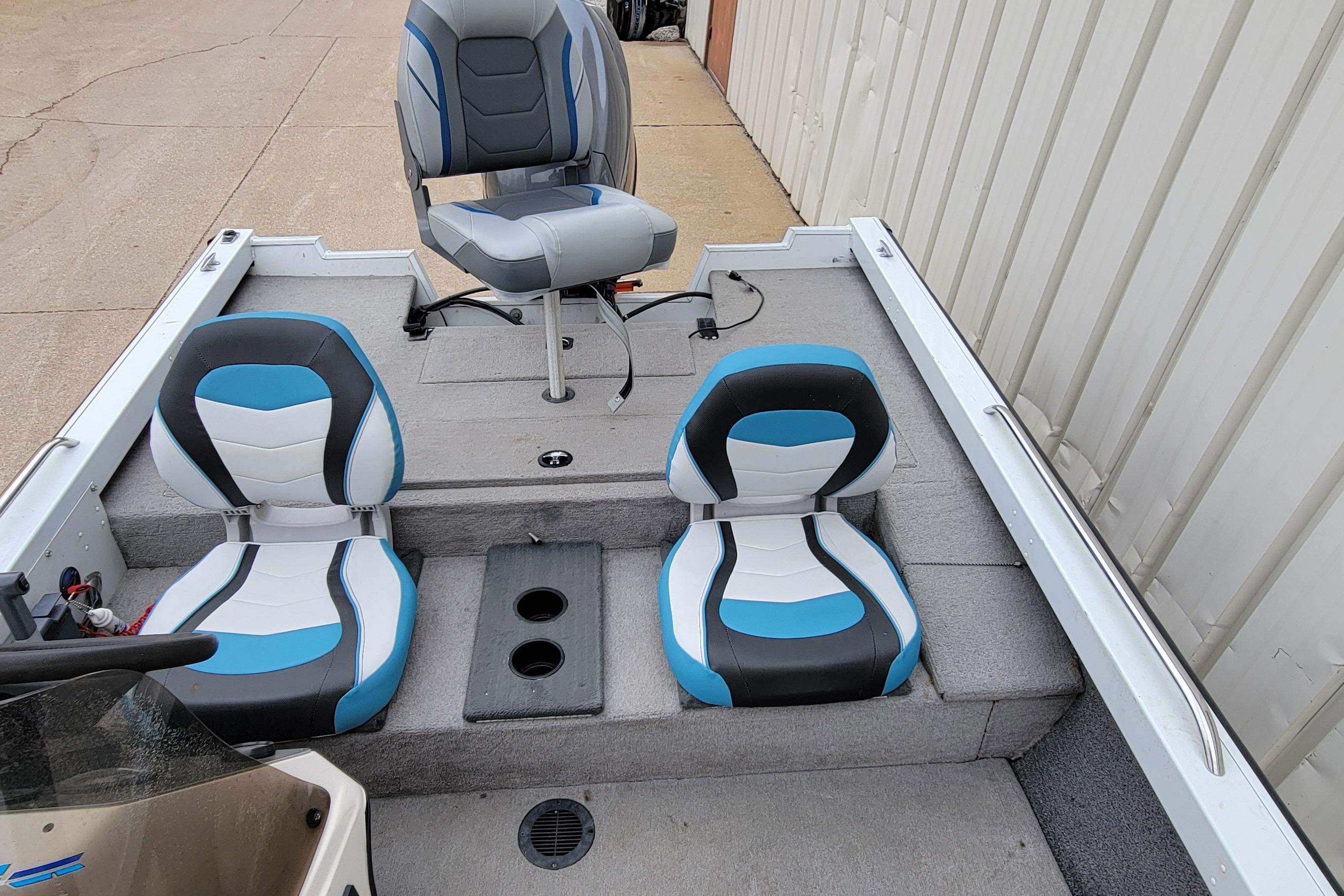 1999 Ranger 107 Cherokee boat interior with blue and white seats, docked beside a building.