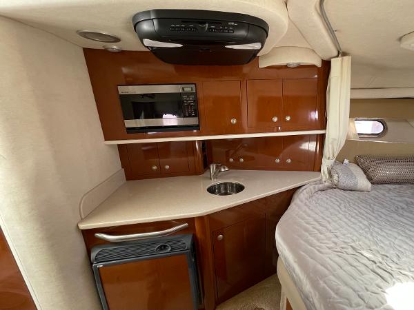 2005 Sea Ray Amberjack 290 interior with kitchenette and bed, featuring wood cabinets and modern appliances.