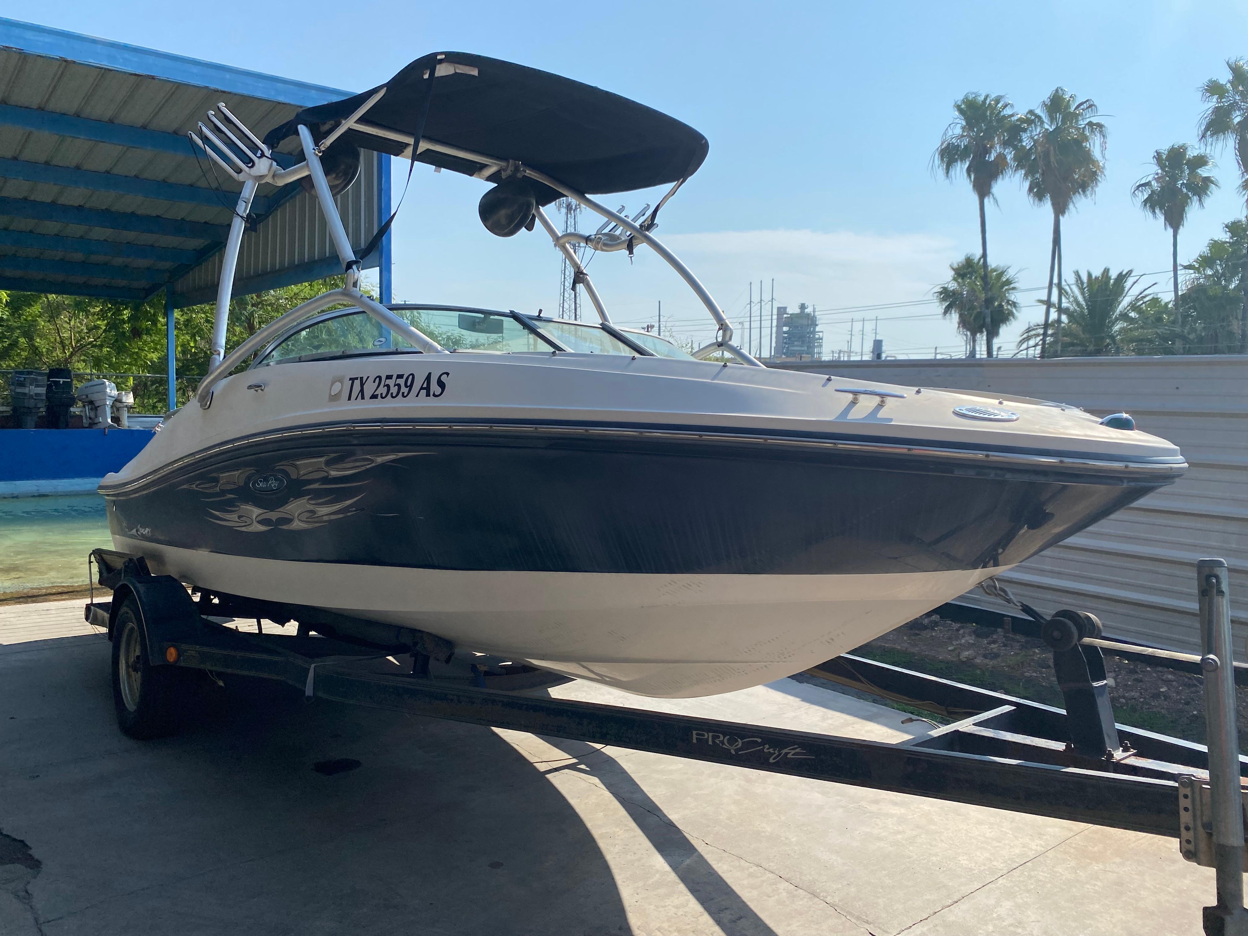 2008 Sea Ray 185 Sport boat on trailer, under a canopy, with palm trees in background.