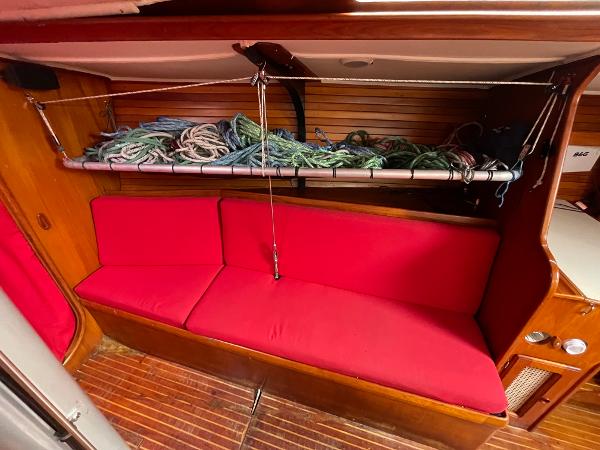 Red-cushioned seating area in 1980 Davidson 44 yacht interior with rope storage above.