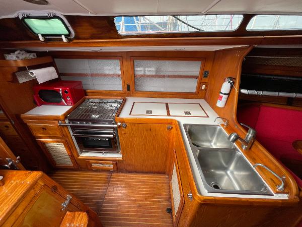 1980 Davidson 44 yacht kitchen with wood cabinetry, dual sinks, stove, and microwave.