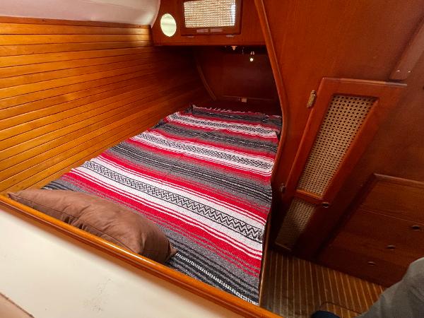Cozy cabin interior of 1980 Davidson 44 sailboat with striped bedding and wooden paneling.