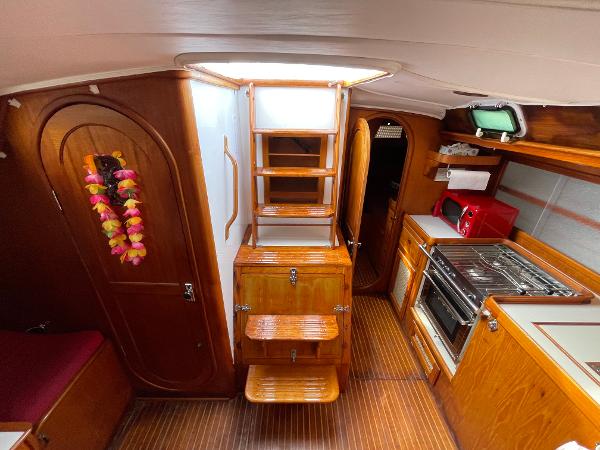 Interior of 1980 Davidson 44 yacht with wooden cabinetry, kitchen, and ladder.
