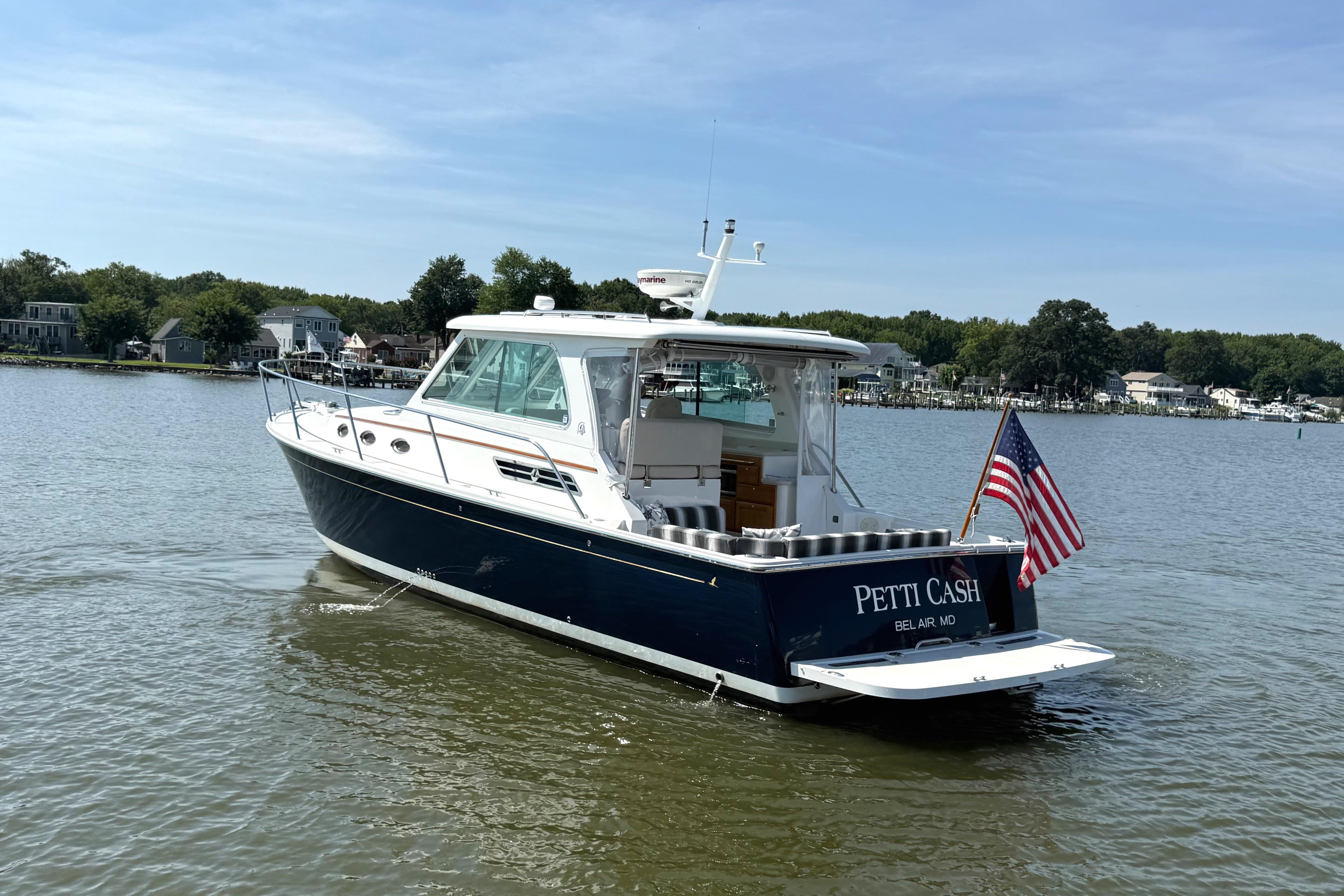 2013 Back Cove 34 boat named u0022Petti Cashu0022 on a calm river with American flag.