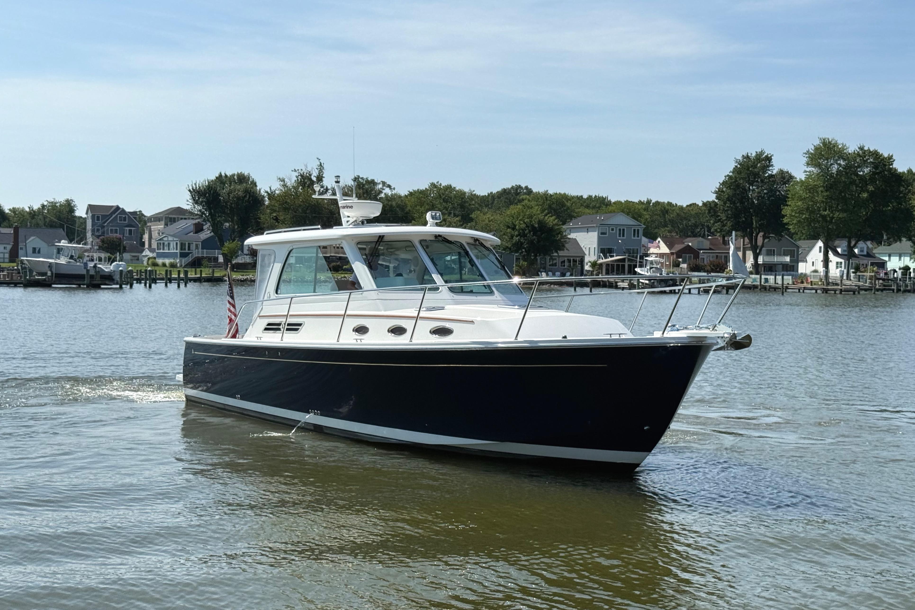 2013 Back Cove 34 boat cruising on a calm river near residential area.