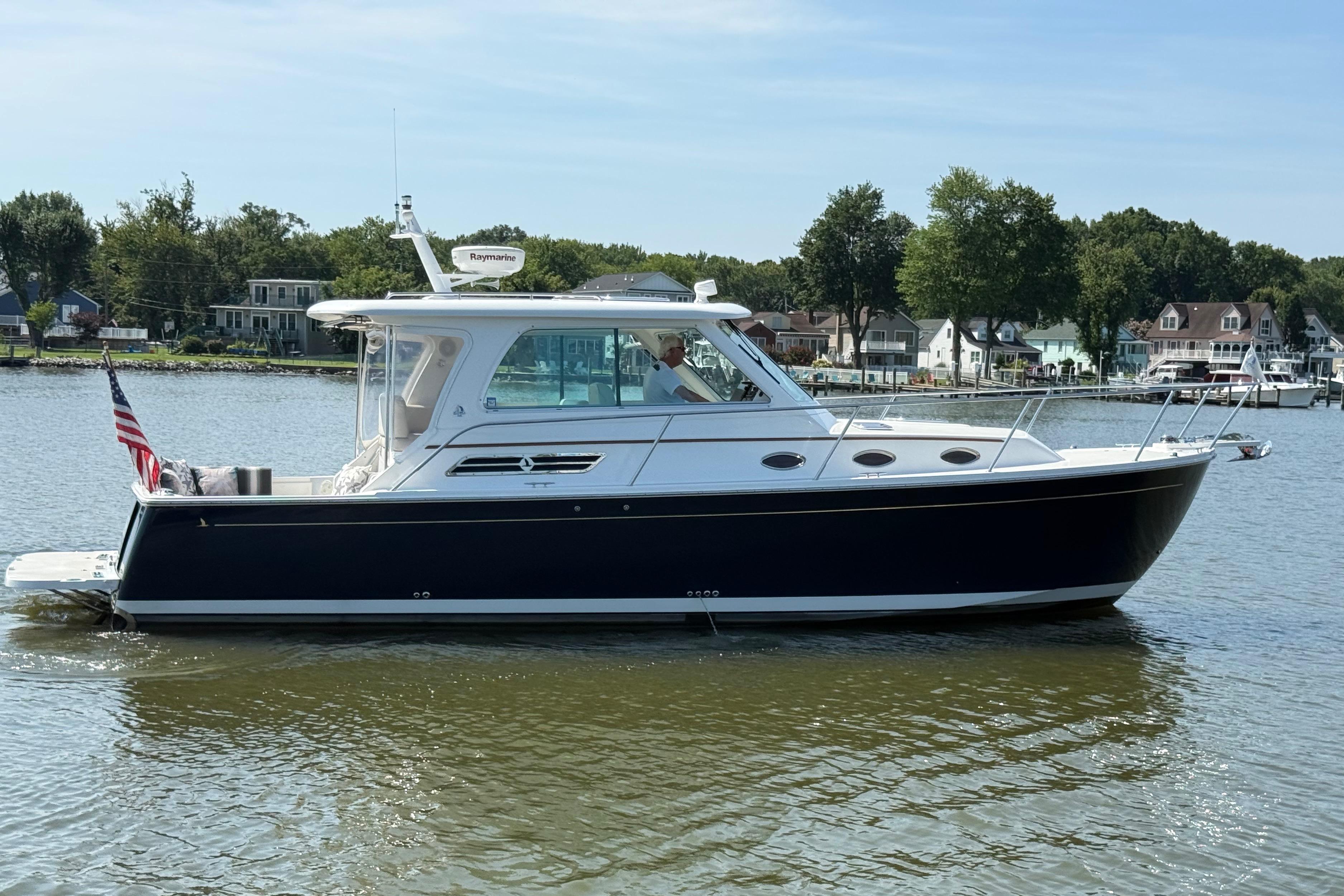 2013 Back Cove 34 boat on calm water with scenic shoreline background.