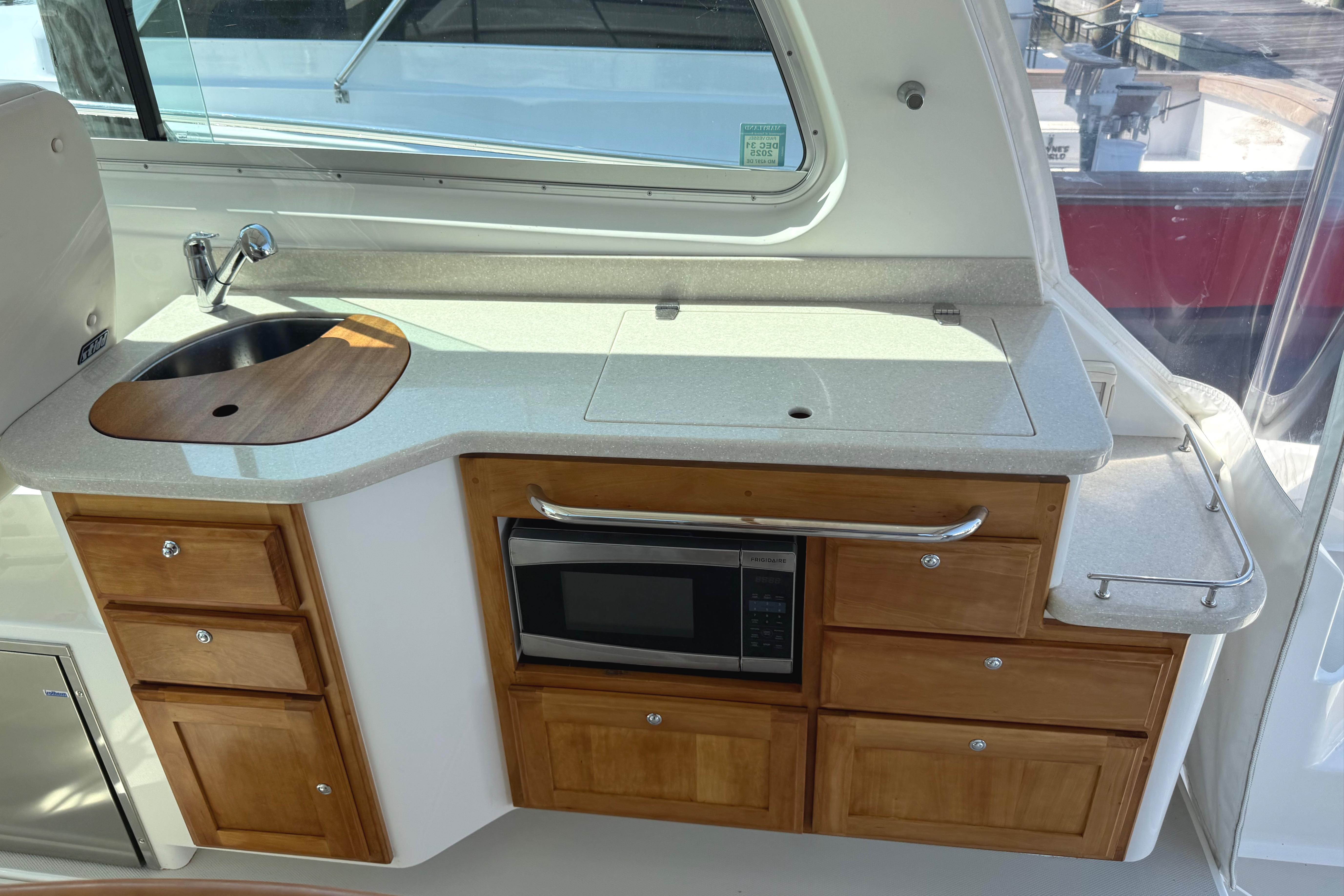 2013 Back Cove 34 yacht kitchenette with sink, microwave, and wooden cabinets.