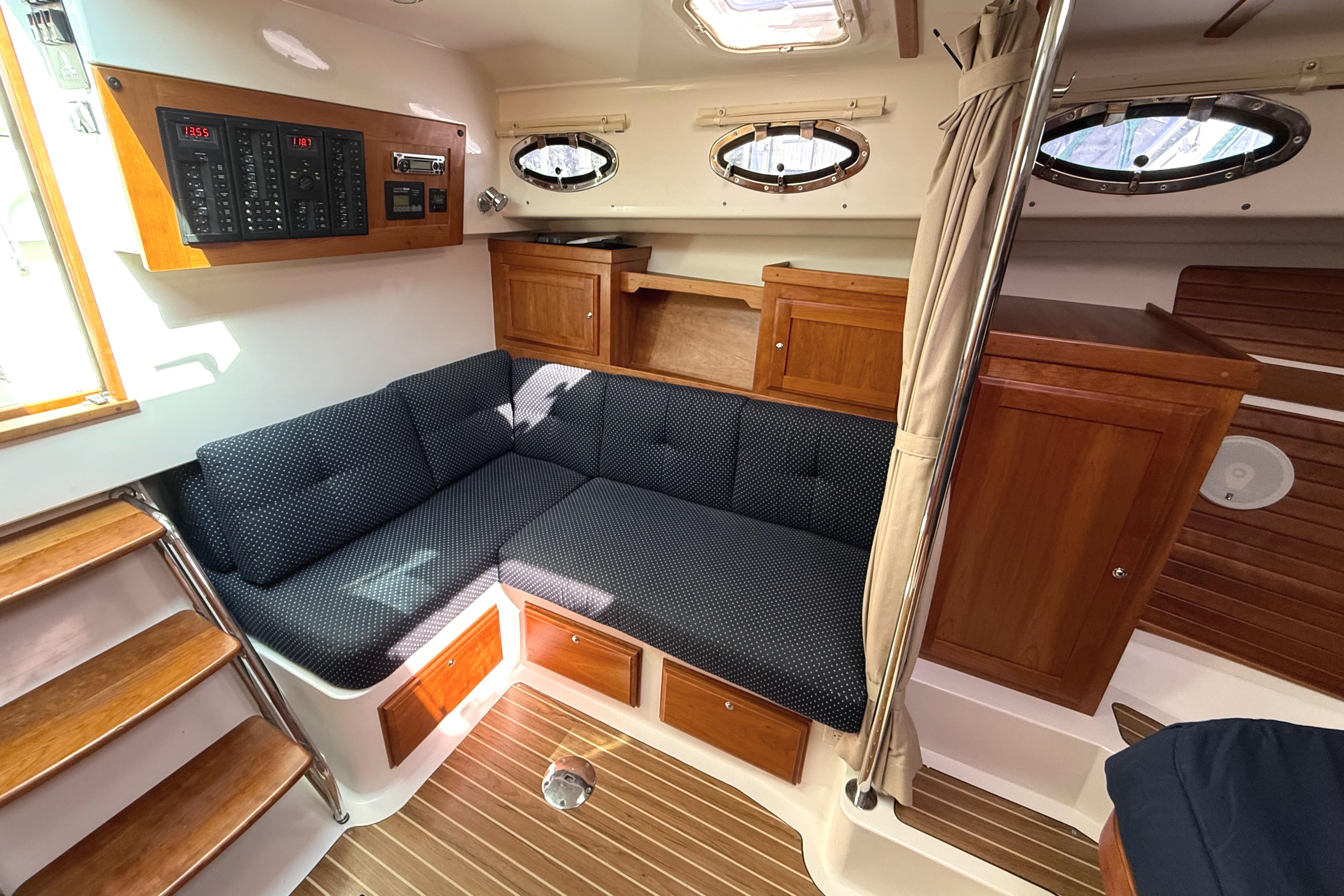 2013 Back Cove 34 interior with cozy seating, wooden cabinetry, and control panel.