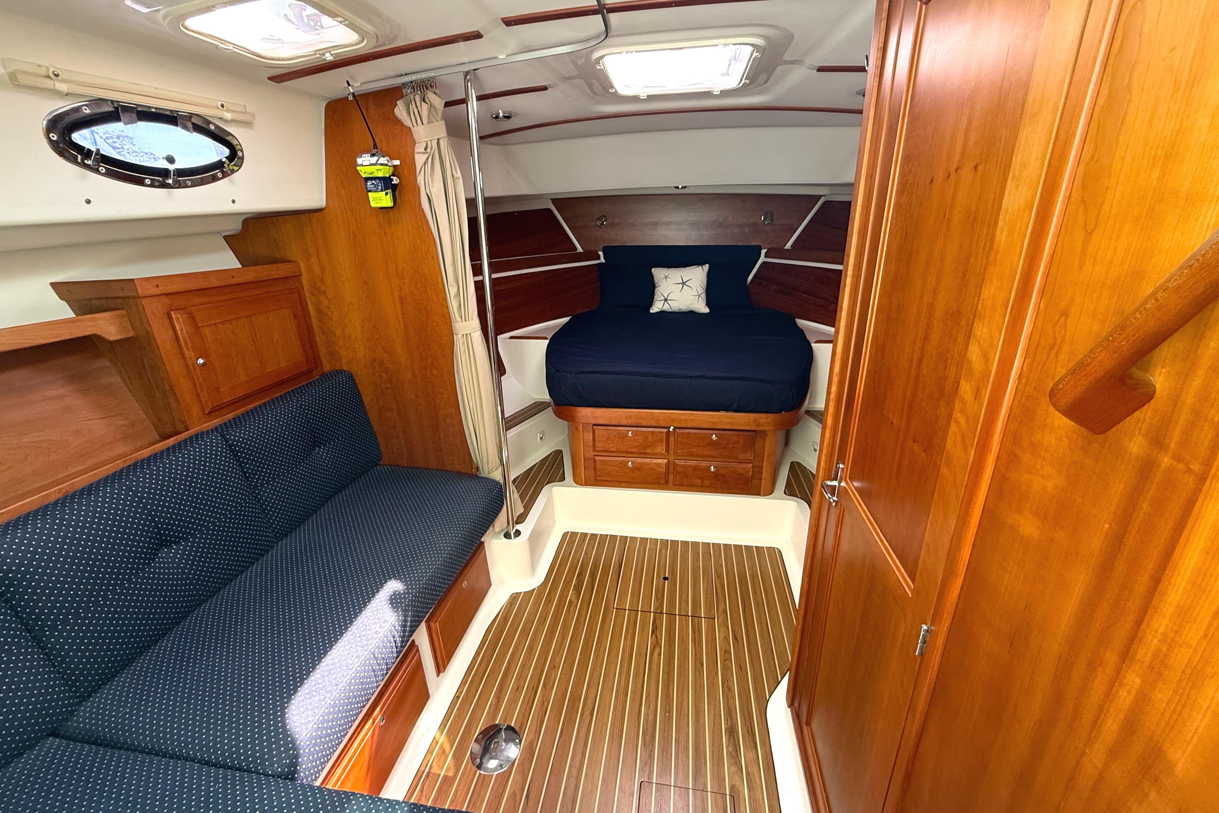 2013 Back Cove 34 interior with wood finish, blue seating, and cozy sleeping area.