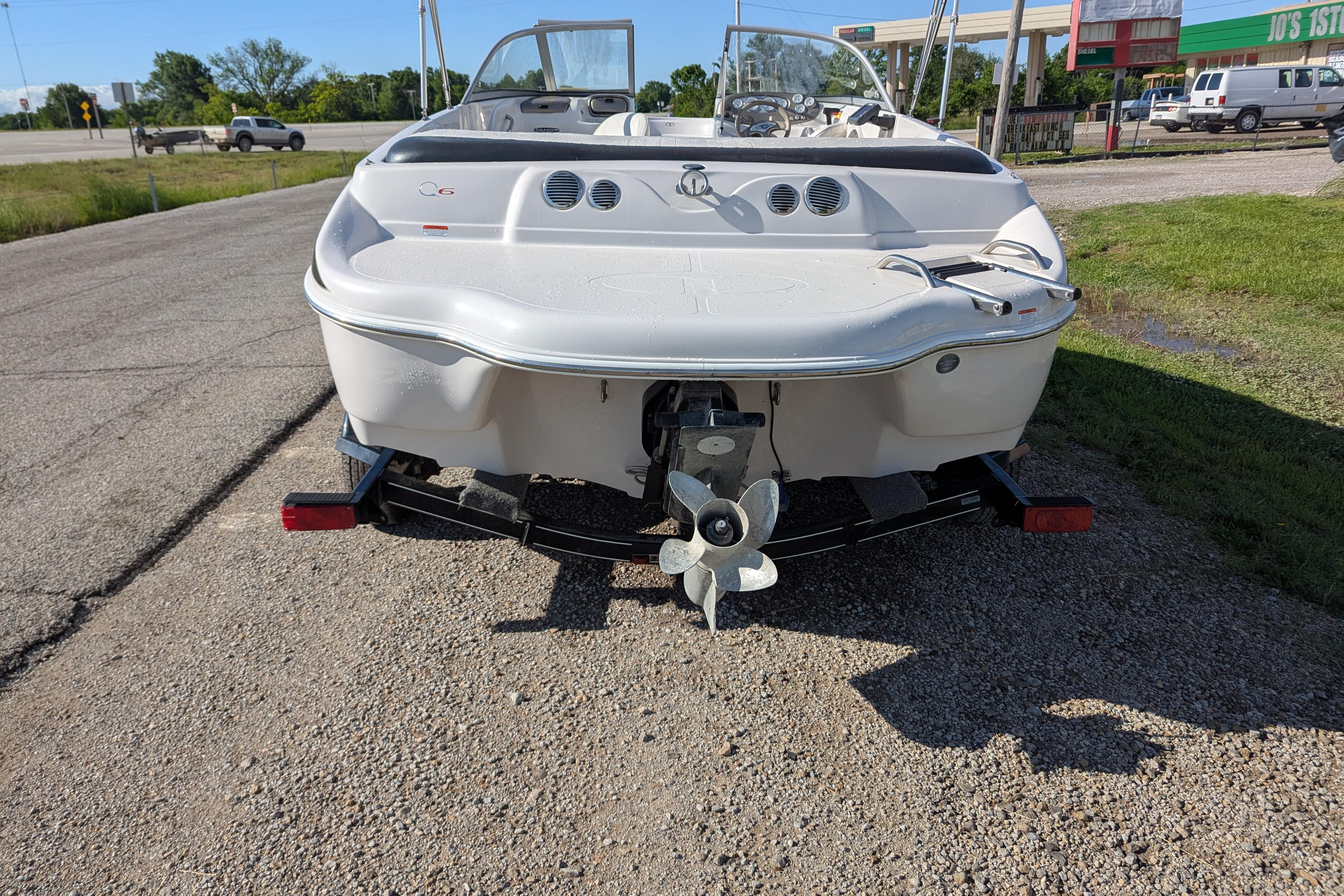 2006 Tahoe Q6 Sport boat, rear view, parked on gravel near road.