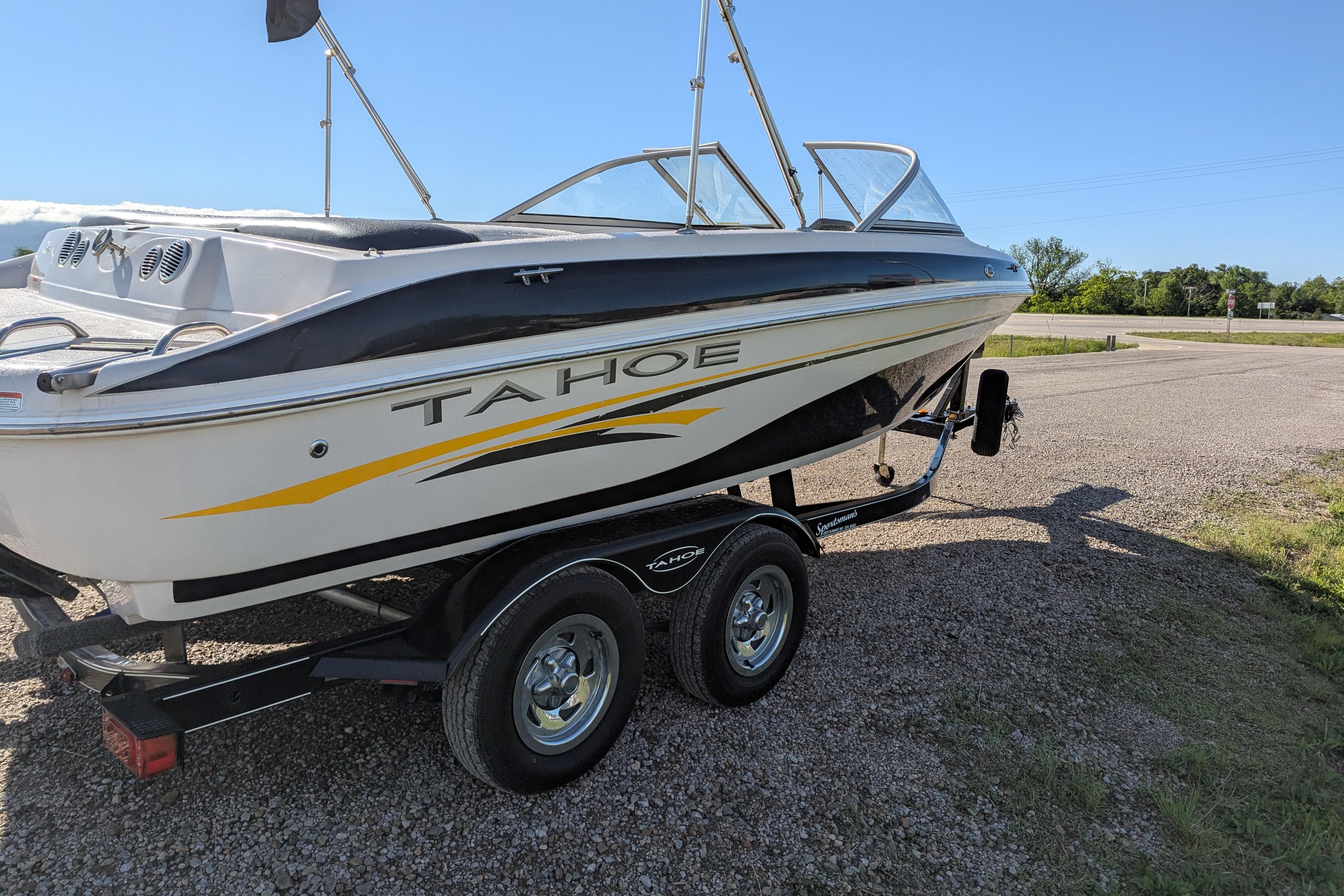 2006 Tahoe Q6 Sport boat on trailer, parked on gravel under clear blue sky.