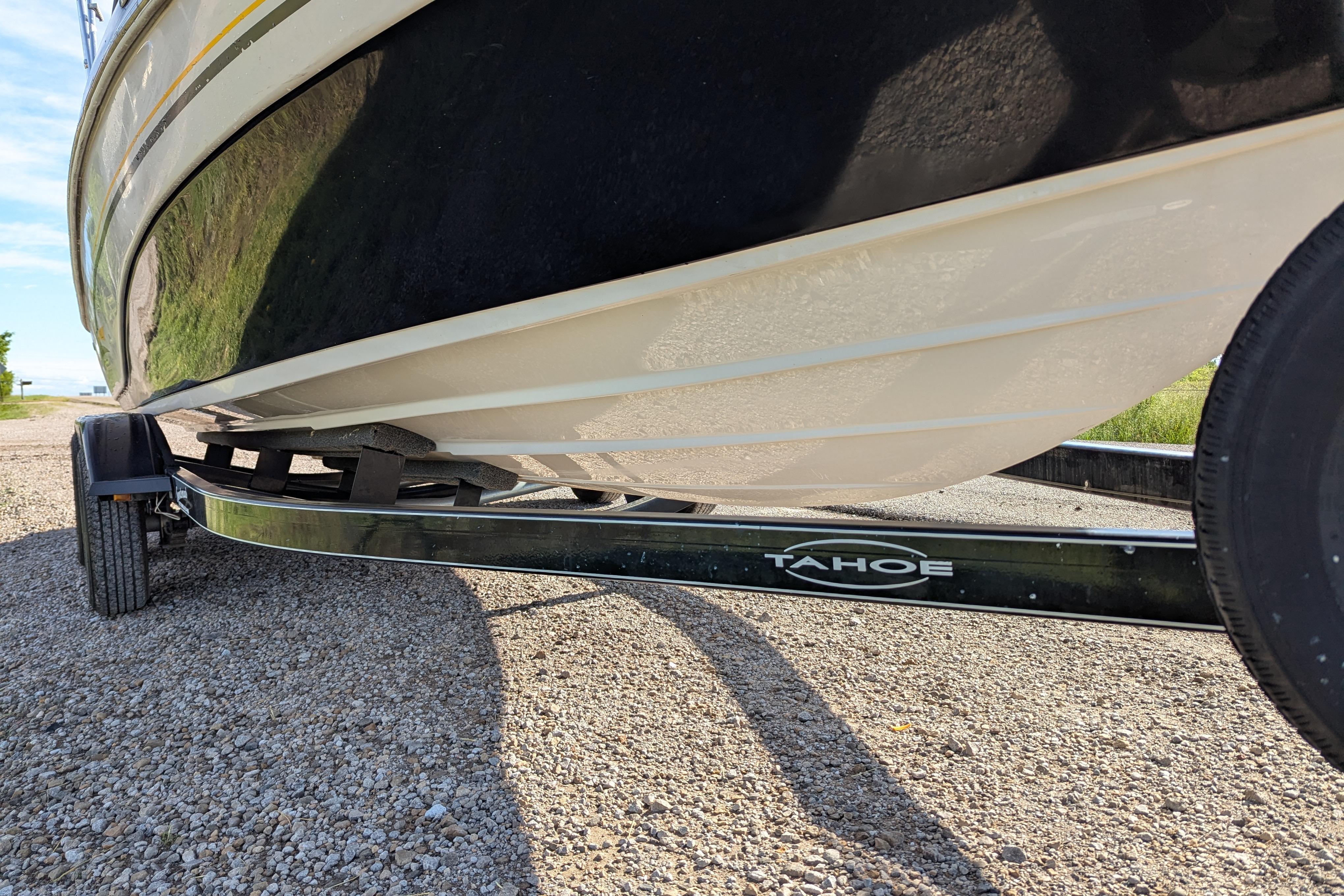 2006 Tahoe Q6 Sport boat on trailer, side view, parked on gravel.