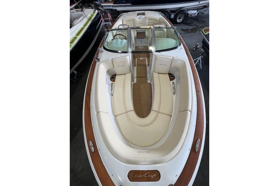 2011 Chris-Craft Launch 22 boat with elegant seating and wooden accents in a showroom.