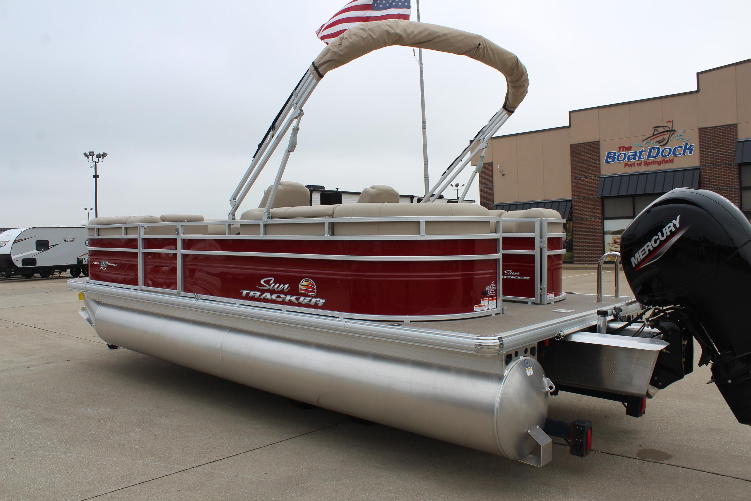 2025 Sun Tracker Party Barge 22 DLX pontoon boat with Mercury engine, docked outdoors.