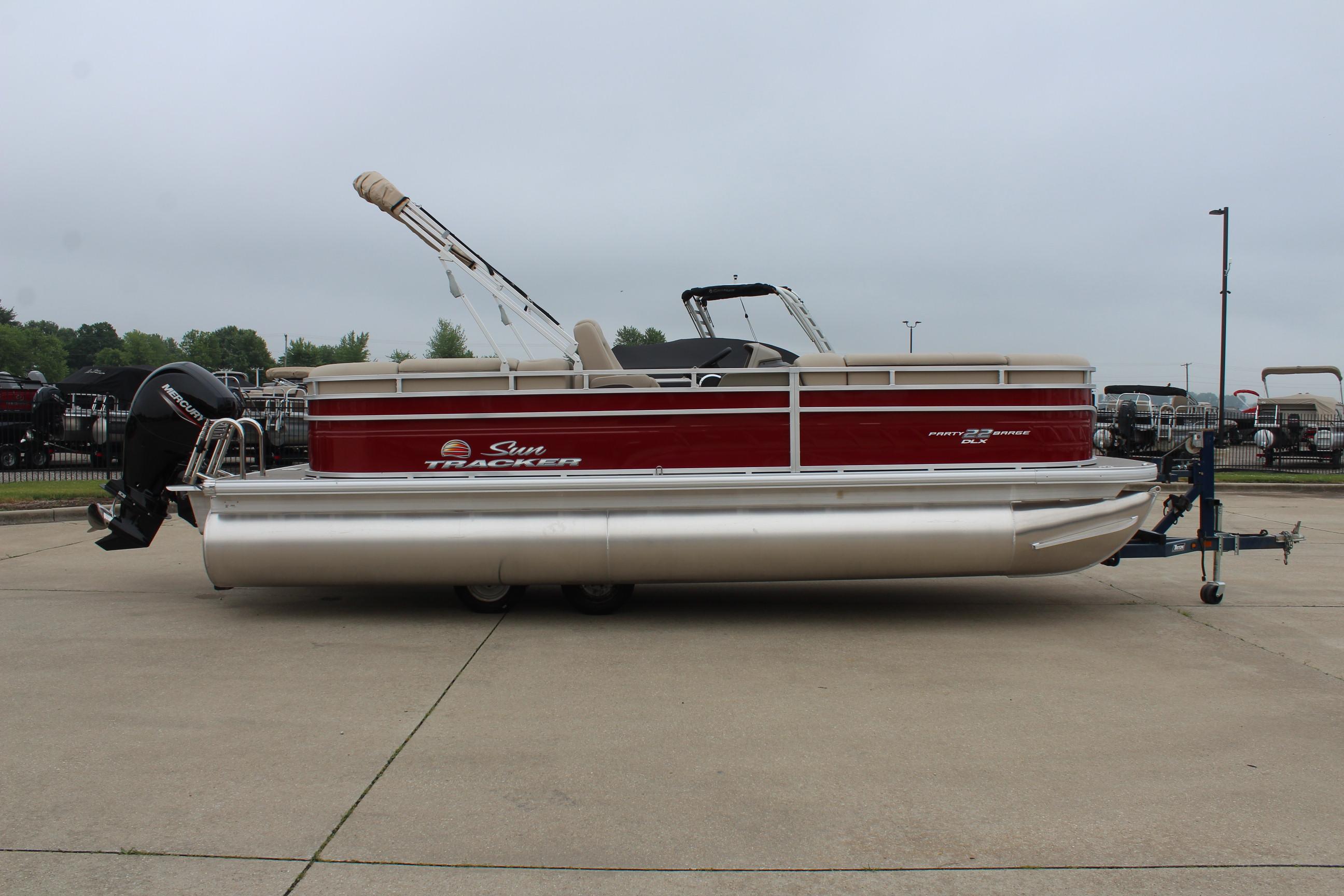 2025 Sun Tracker Party Barge 22 DLX pontoon boat on trailer, parked outdoors.