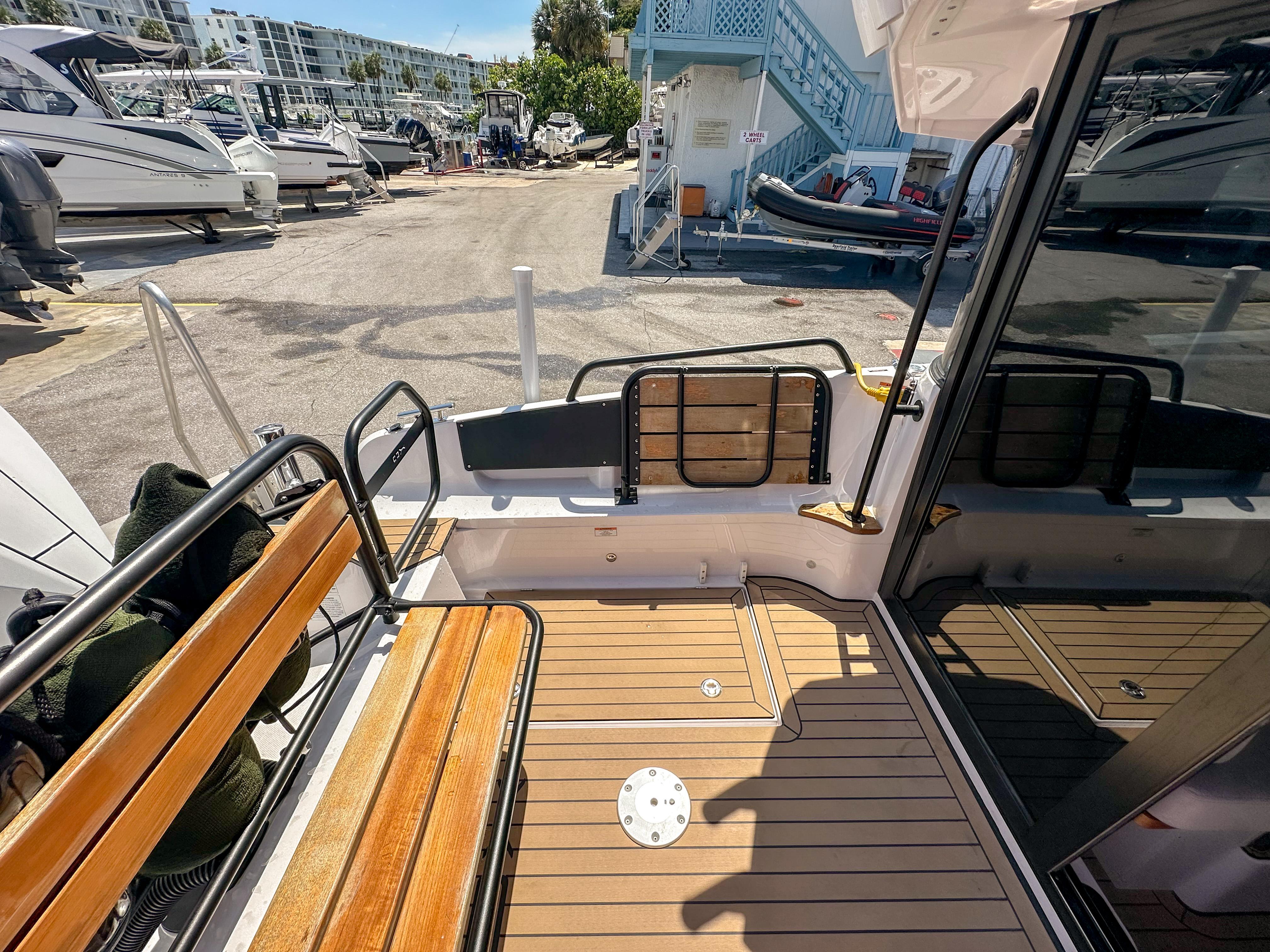 XO Boats-EXPLR 10 Sport Plus 2024 -FL-US-2024 XO Boats EXPLR 10 Sport Plus deck with wooden seating and marina view.-9818089 | Thumbnail