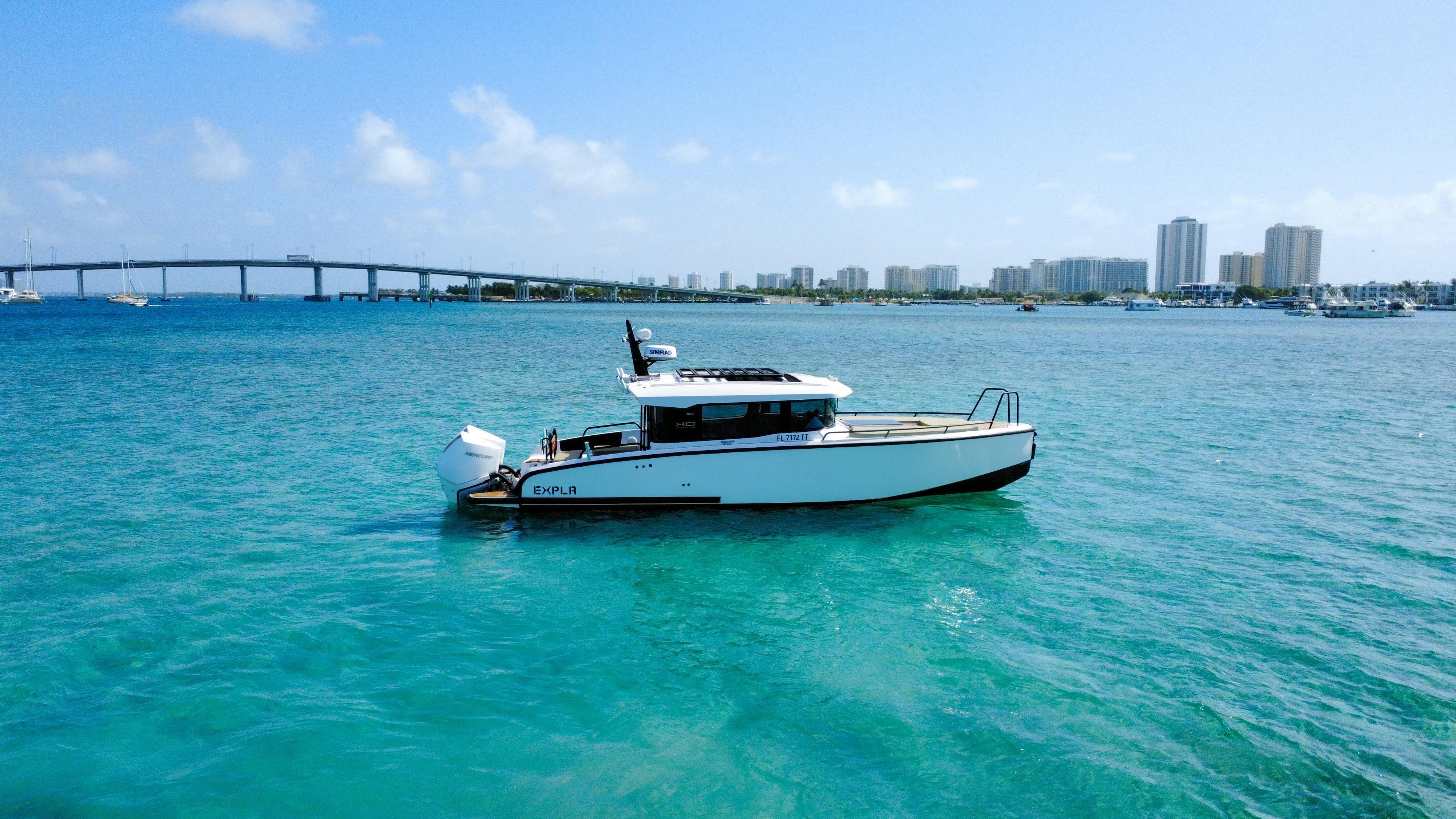 XO Boats-XO Boats EXPLR 10S Plus 2024 -FL-US-2024 XO Boats EXPLR 10S Plus cruising in clear blue waters near a cityscape.-9818089 | Thumbnail