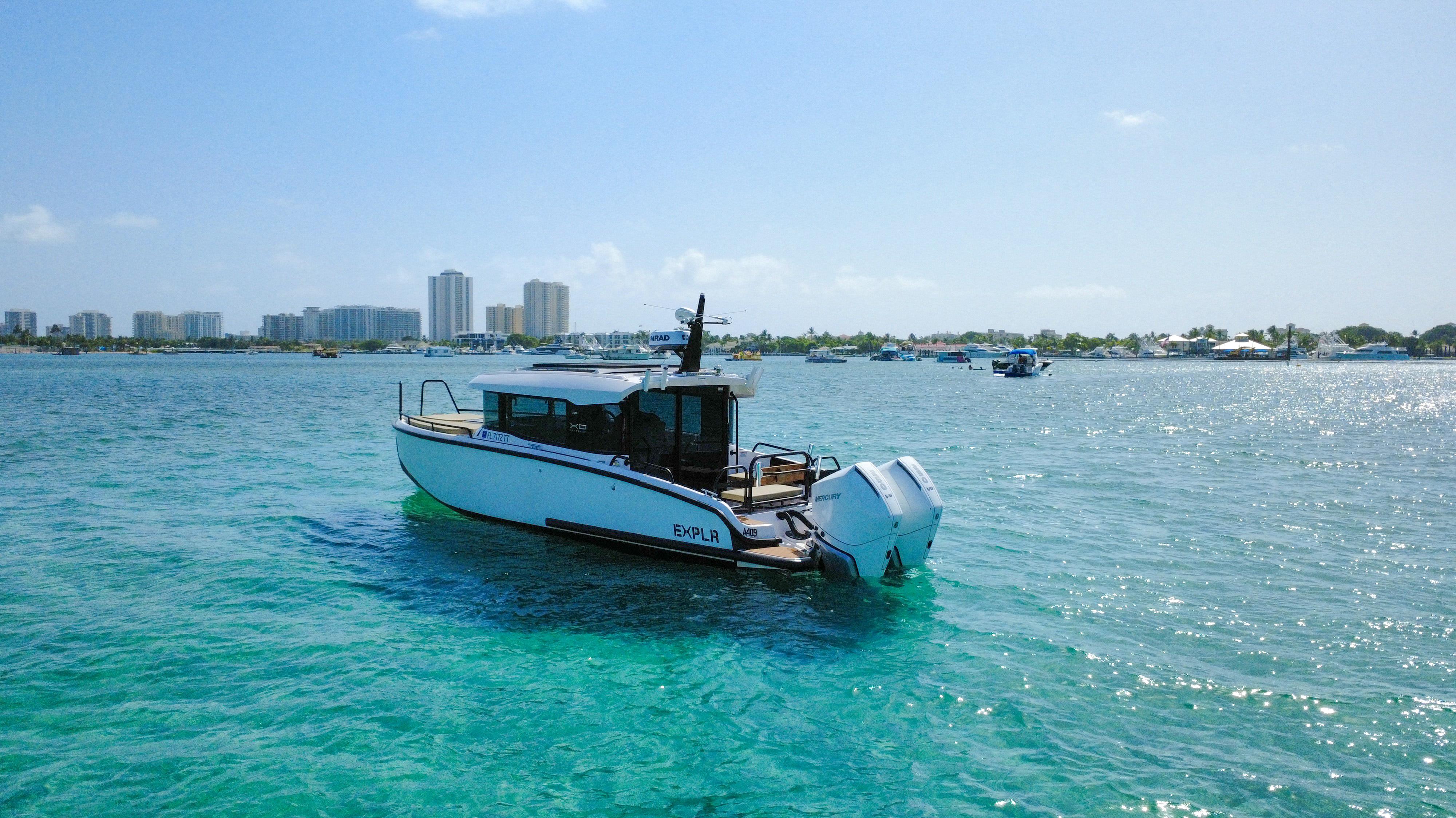 XO Boats-XO Boats EXPLR 10S Plus 2024 -FL-US-2024 XO Boats EXPLR 10S Plus cruising on clear blue water near a city skyline.-9818089 | Thumbnail