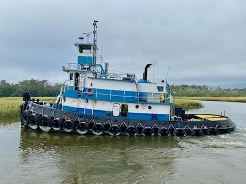 Commercial-Model Bow Tug 1961 -FL-US-1961 Commercial Model Bow Tug navigating a river with lush greenery in the background.-9787034