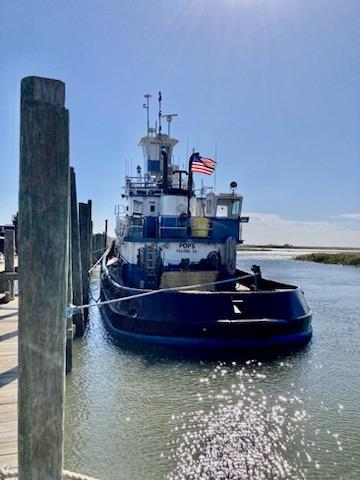 Commercial-Model Bow Tug 1961 -FL-US-A 1961 Commercial Model Bow Tugboat docked, with an American flag, under a clear blue sky.-9787034