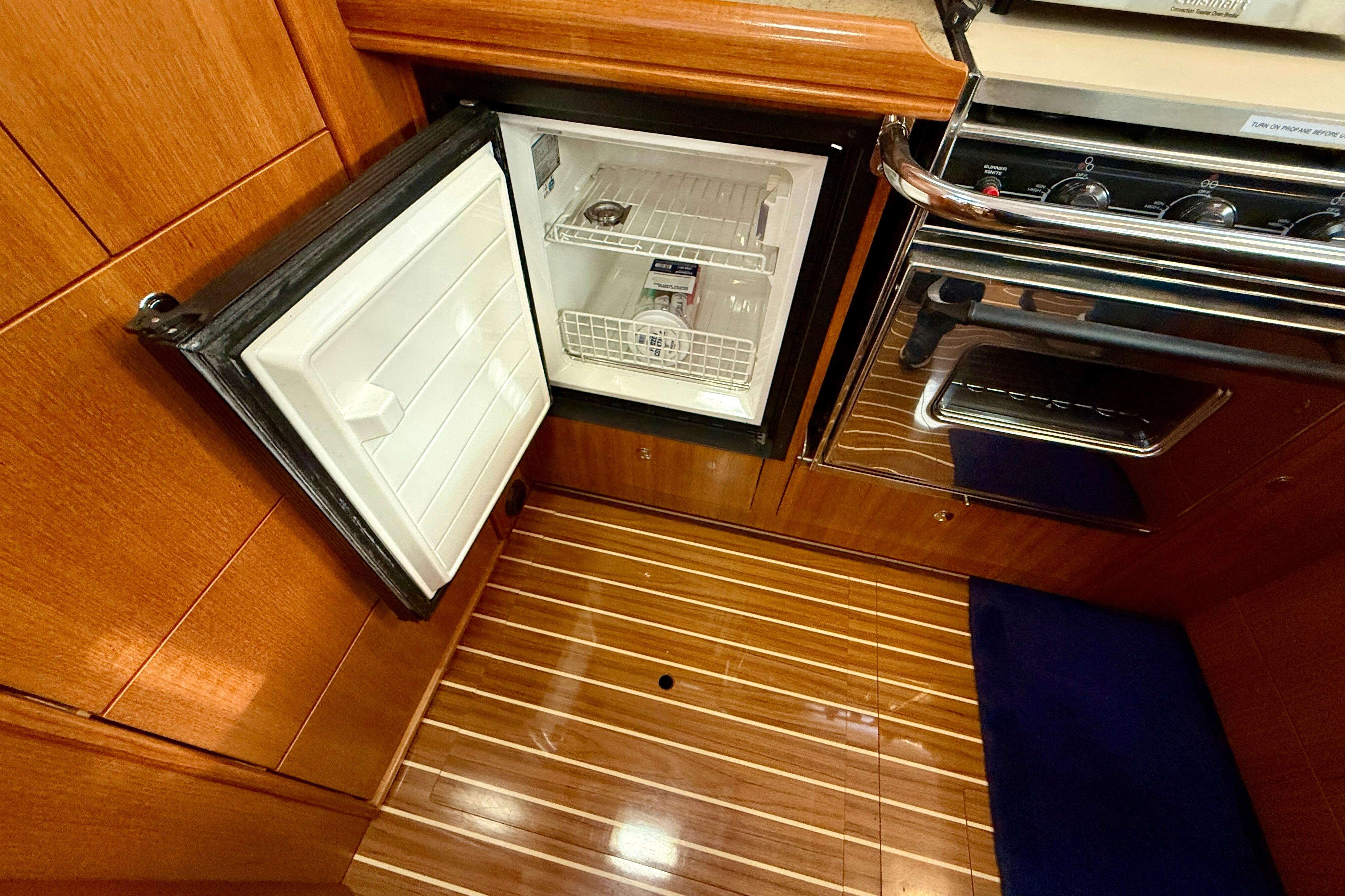 2007 Hunter 44 Deck Salon interior with open fridge and stove, showcasing wood finish.