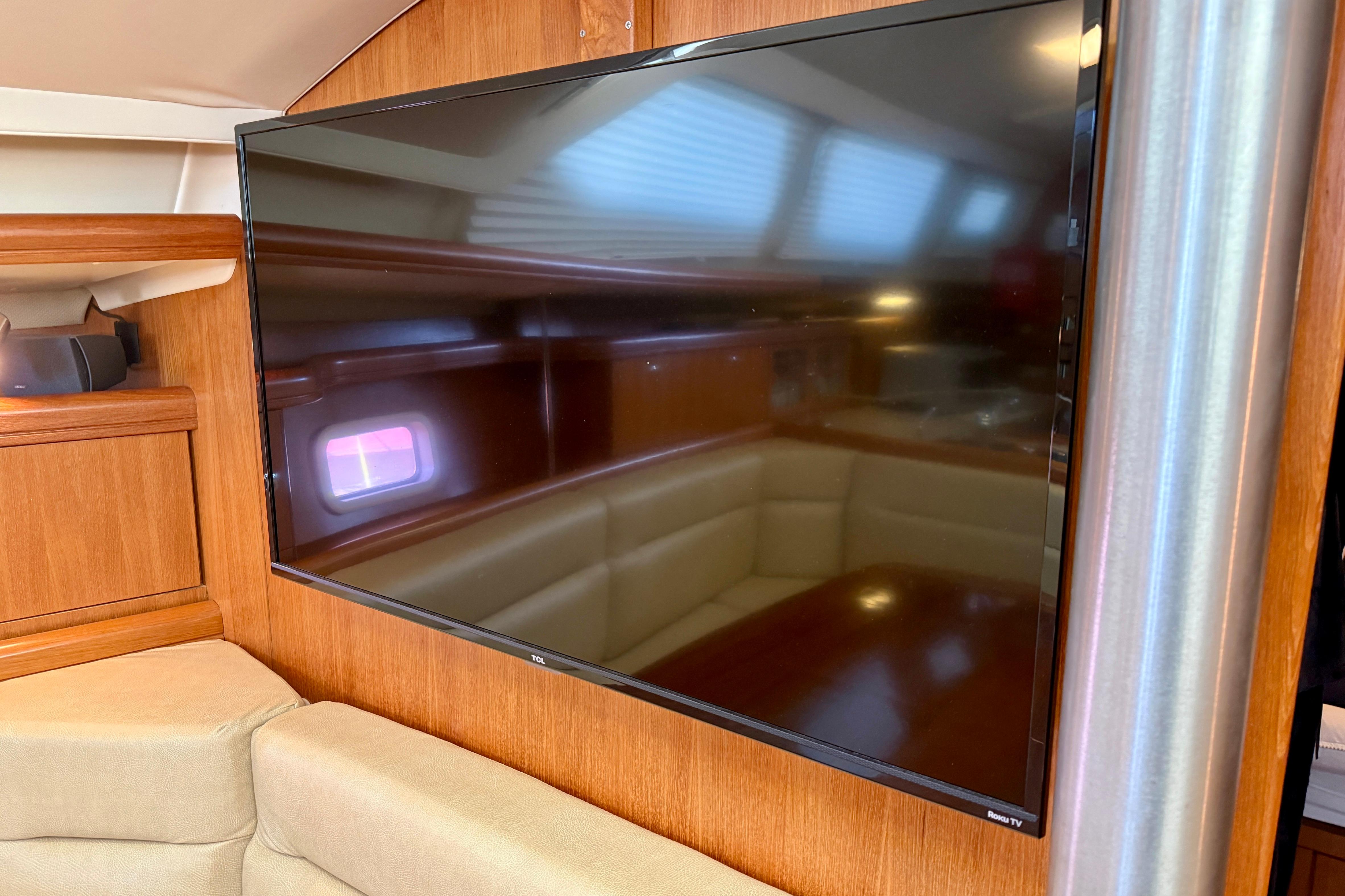 Flat-screen TV in 2007 Hunter 44 Deck Salon yacht interior, featuring wood paneling and seating.
