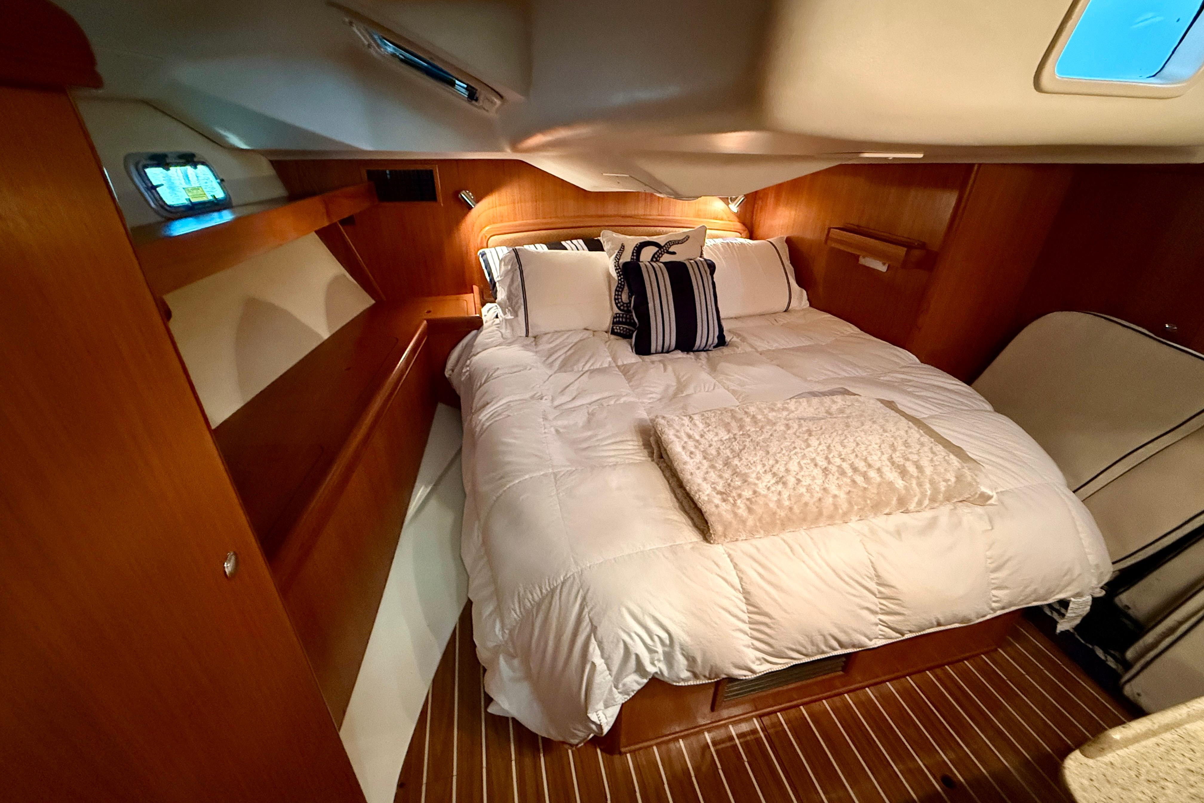 Cozy bedroom in 2007 Hunter 44 Deck Salon yacht with wooden interior and plush bedding.