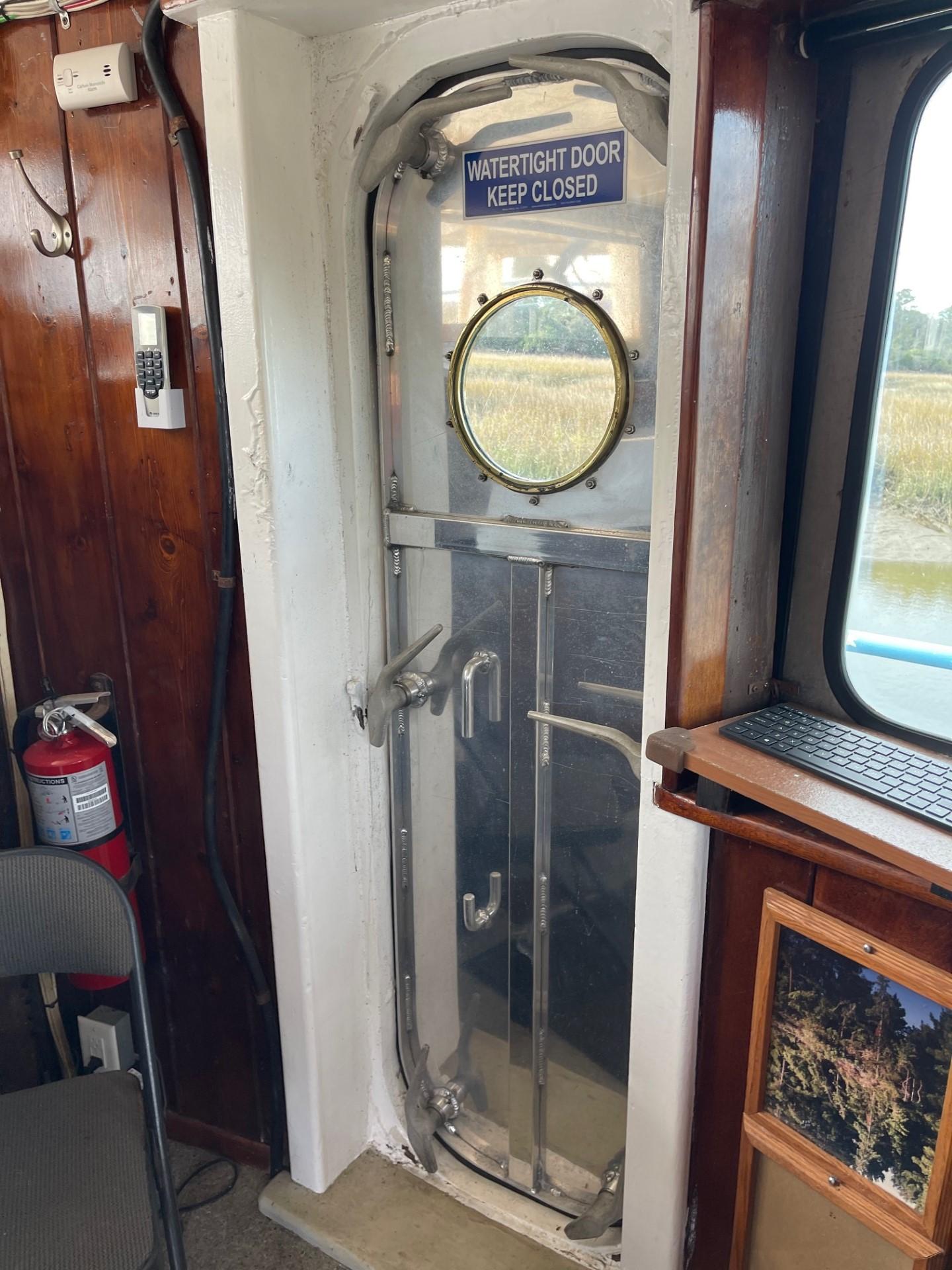 Commercial-Model Bow Tug 1961 -FL-US-Watertight door on 1961 Commercial Model Bow Tug, interior view with porthole and safety sign.-9787034 | Thumbnail