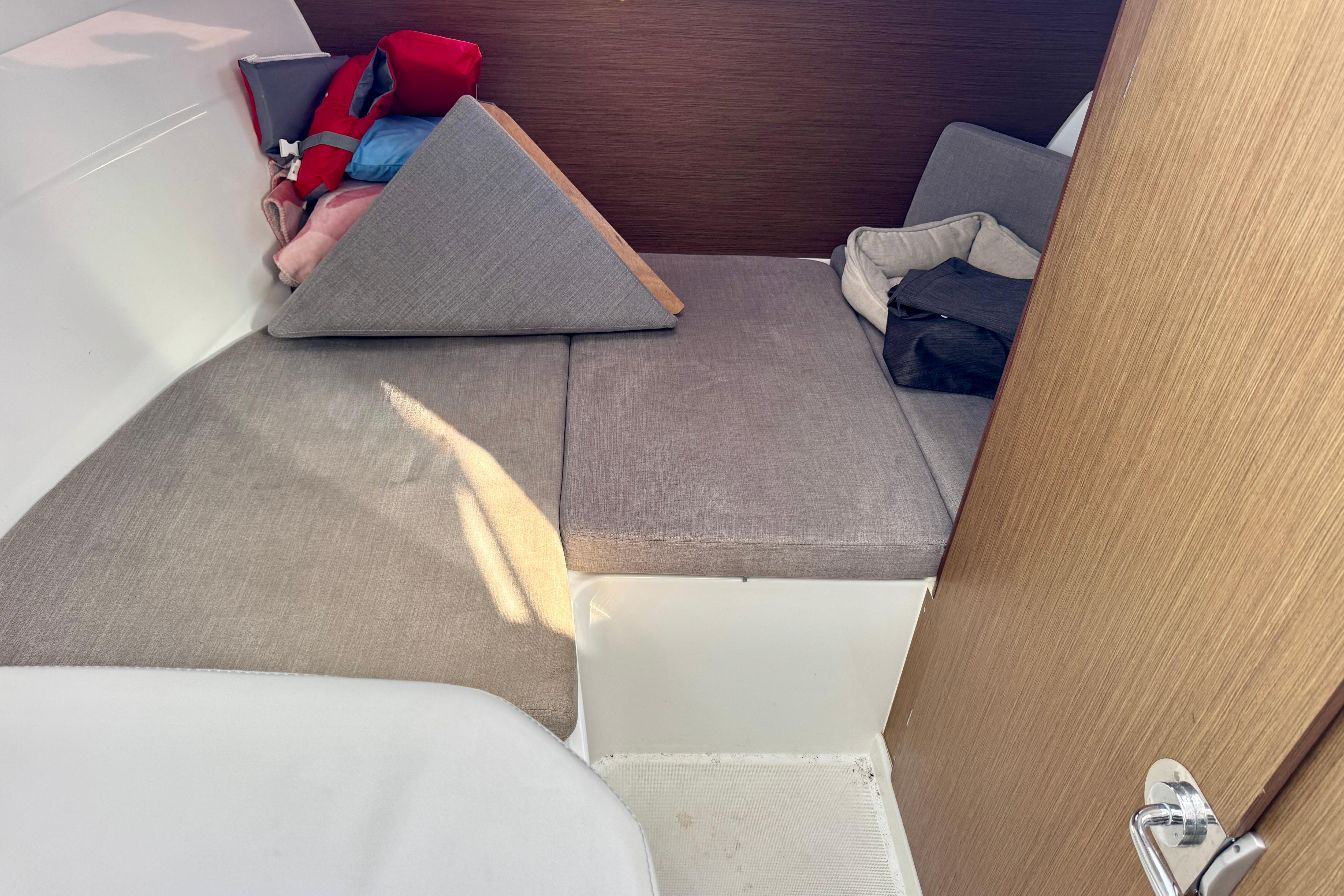 Cozy cabin interior of 2022 Beneteau Antares 7 with cushions and life jackets.