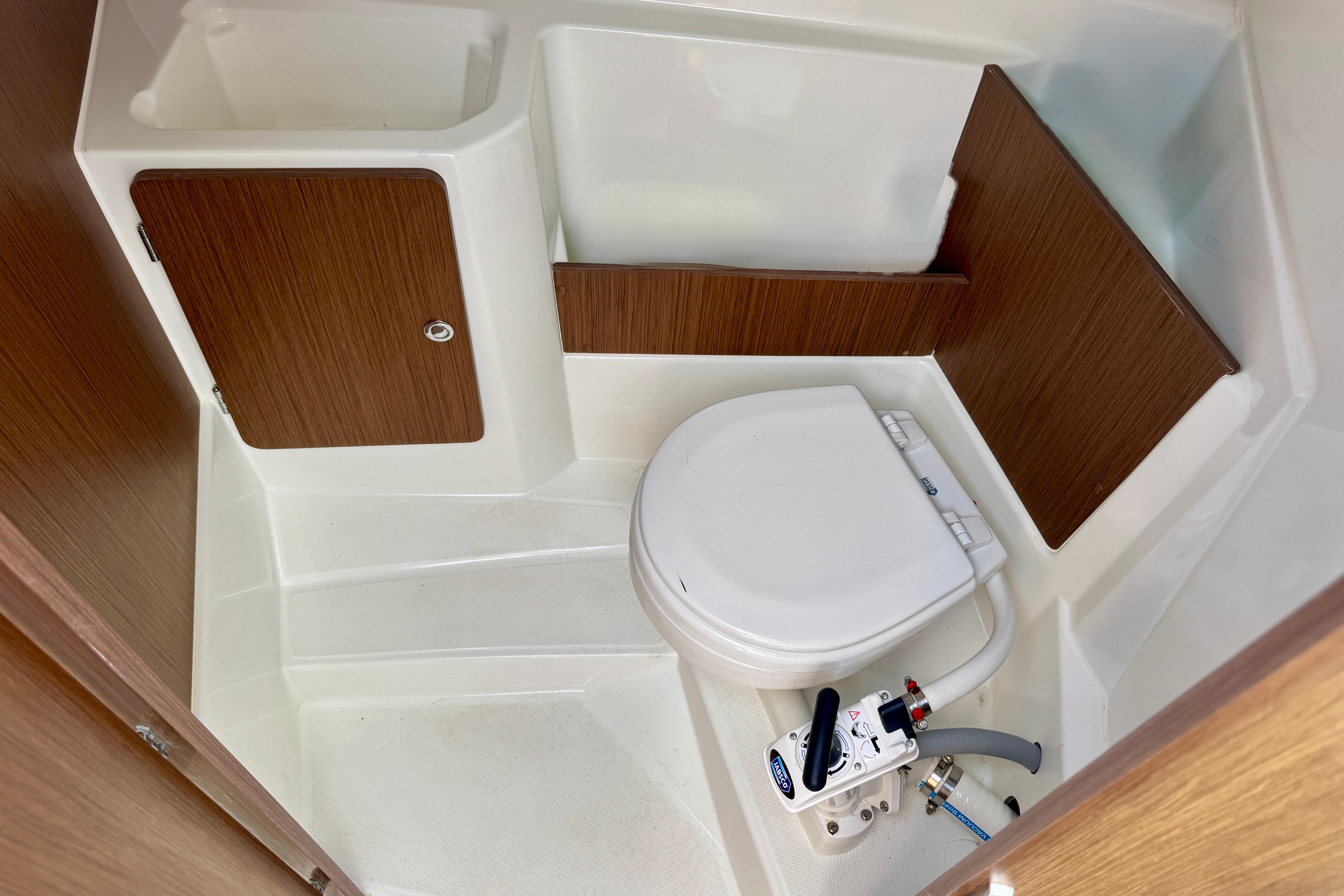 2022 Beneteau Antares 7 boat bathroom with compact toilet and wooden cabinetry.