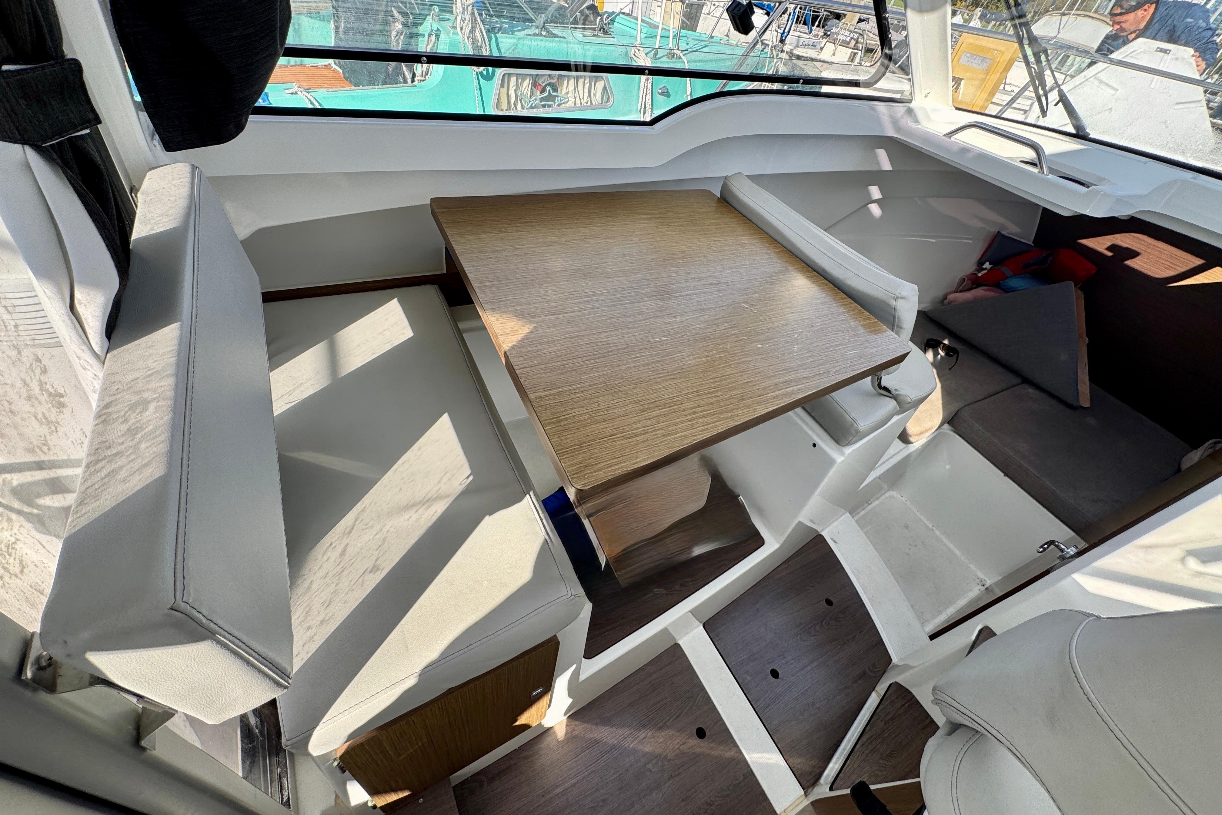 Interior of 2022 Beneteau Antares 7 with seating and wooden table.