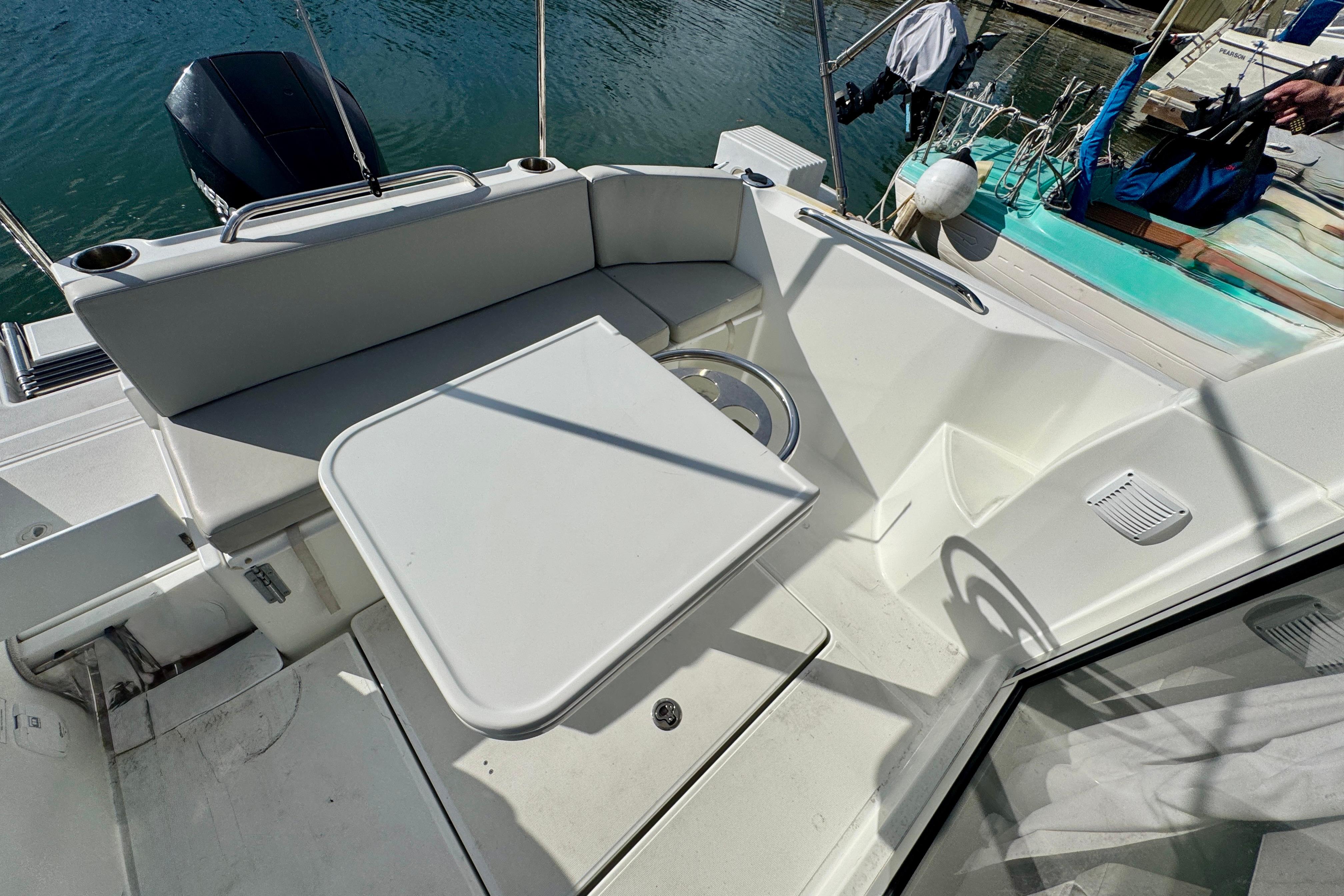 Beneteau Antares 7 (2022) boat deck with seating and table, docked by water.
