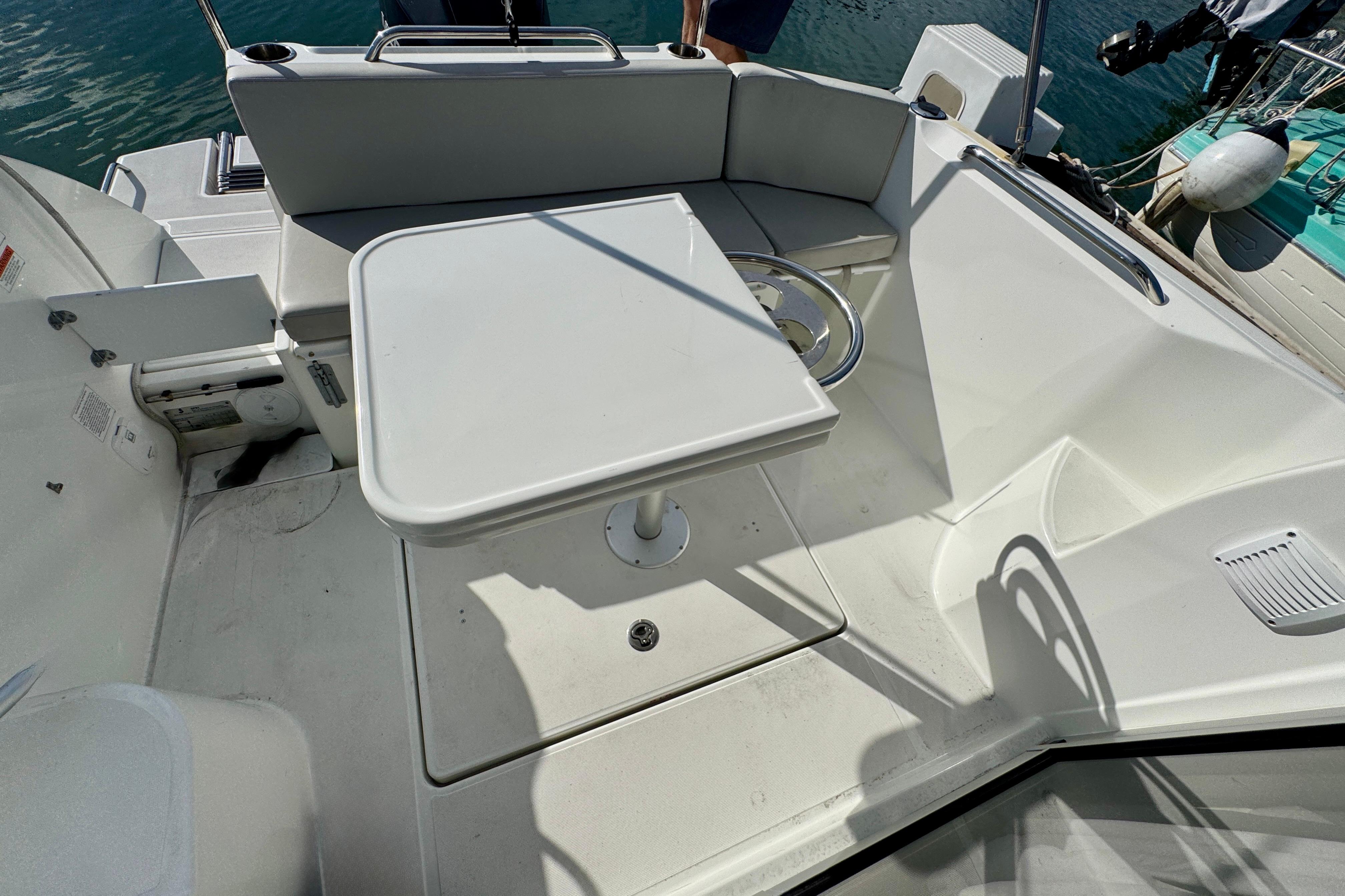 Beneteau Antares 7 (2022) cockpit with seating and table, docked by the water.
