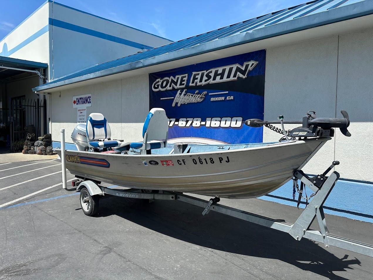 1998 Klamath 14 DLX boat on trailer outside a fishing store.