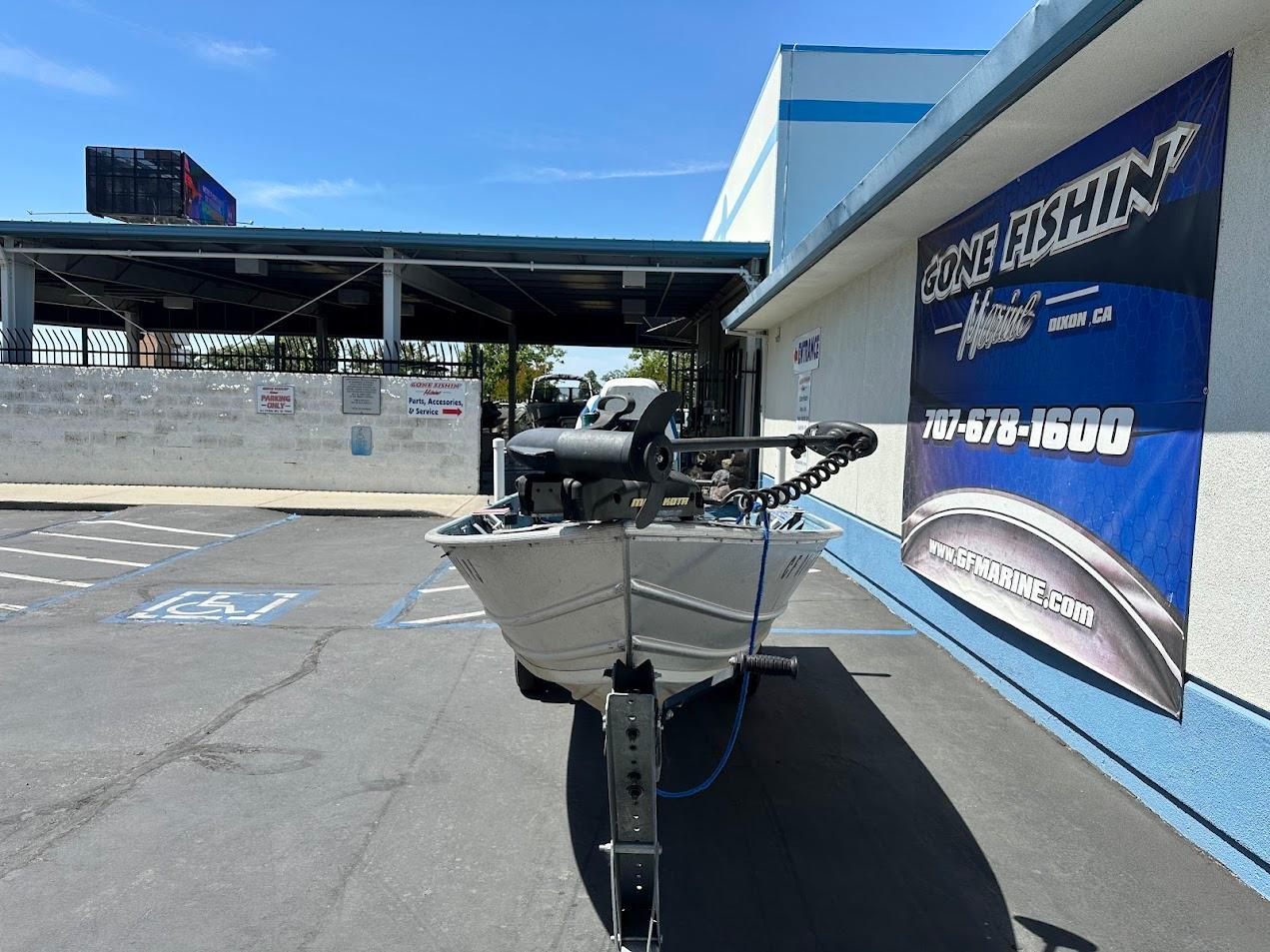 1998 Klamath 14 DLX boat parked outside Gone Fishin' Marine store.