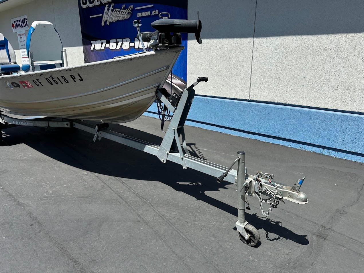 1998 Klamath 14 DLX boat on trailer, parked outside a building.