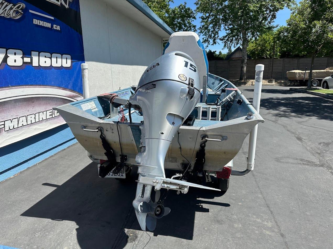 1998 Klamath 14 DLX boat with a 15 HP outboard motor, parked outdoors.