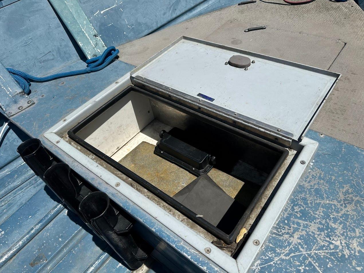 Open storage compartment on a 1998 Klamath 14 DLX boat, featuring rod holders and blue interior.