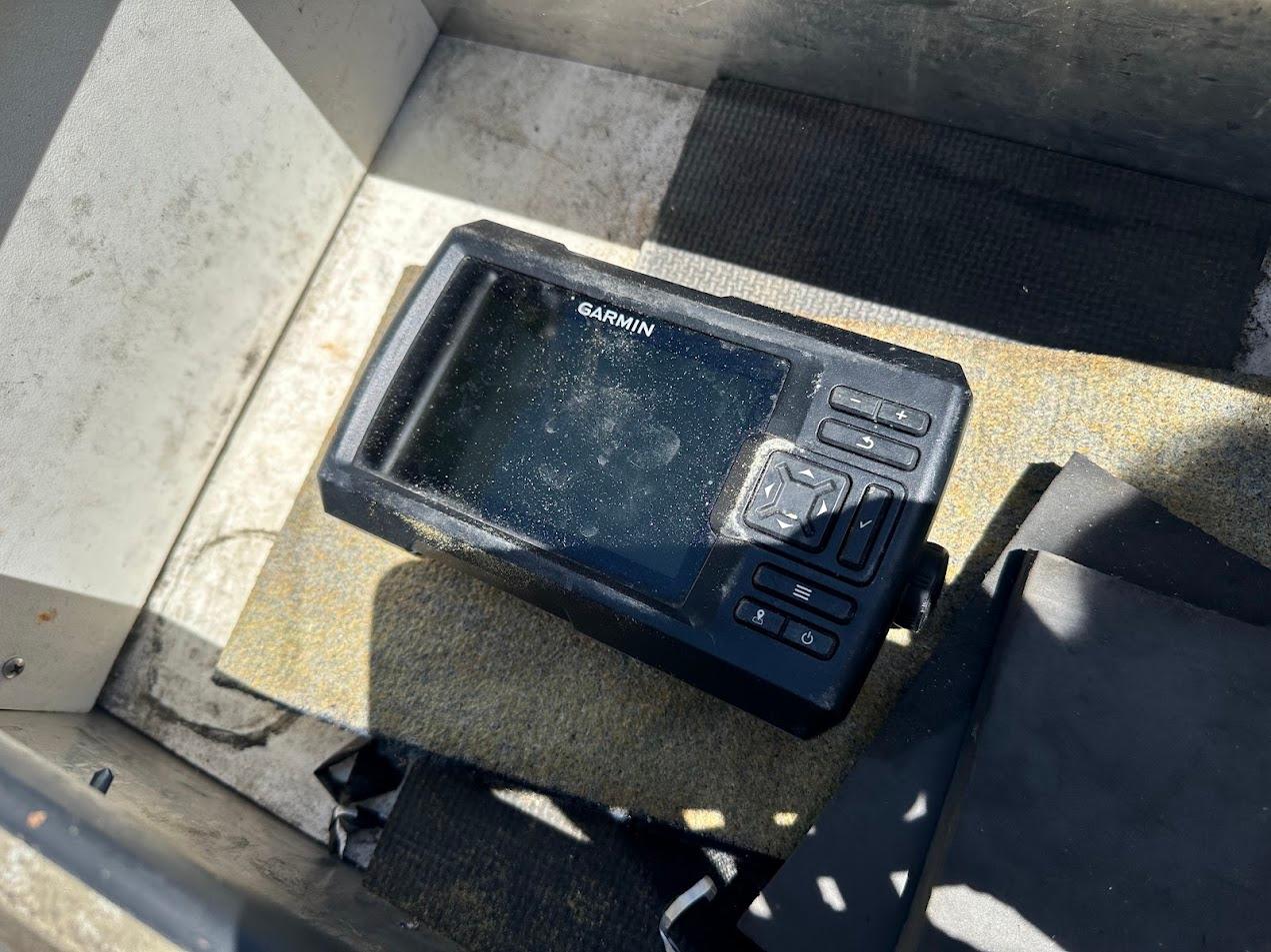Garmin device on 1998 Klamath 14 DLX boat floor, sunlight casting shadows.
