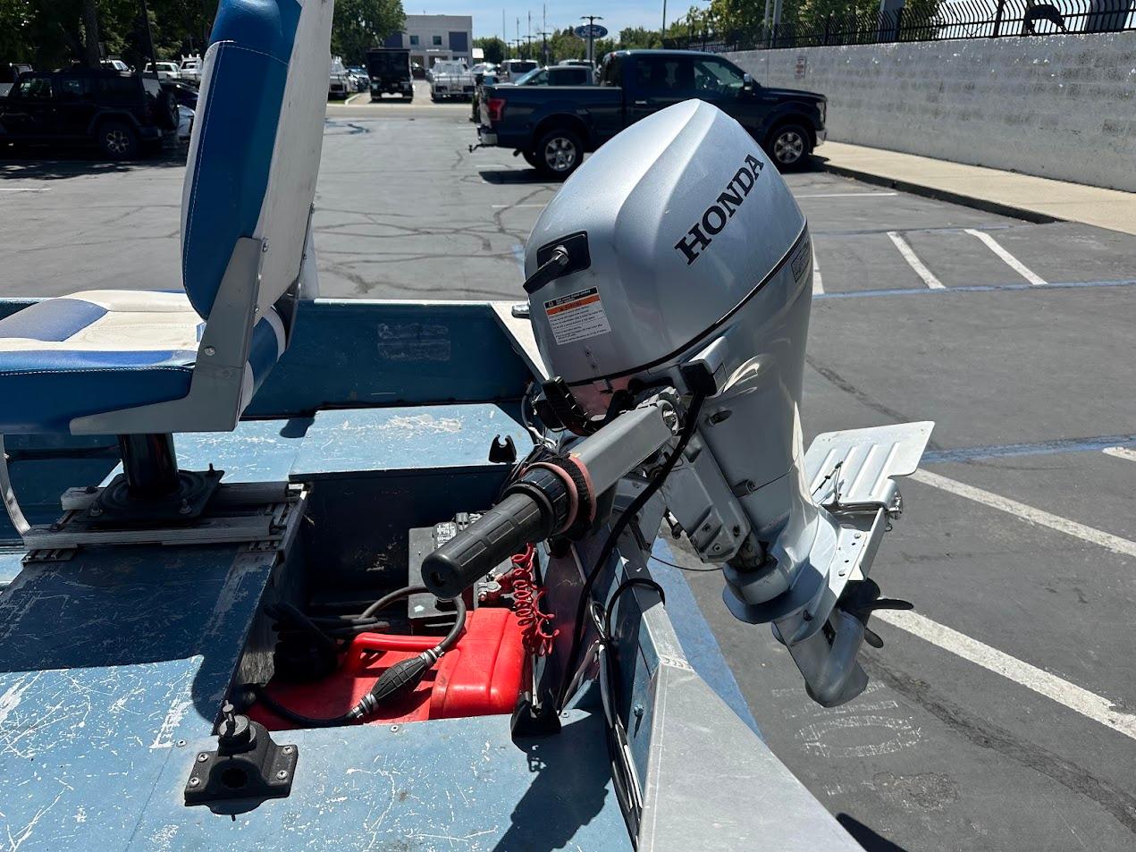 1998 Klamath 14 DLX boat with Honda outboard motor in a parking lot.