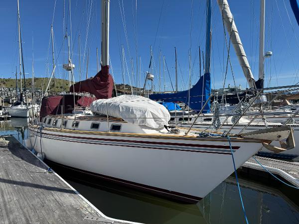 1984 Endeavour 38 sailboat docked in a marina under clear blue skies.