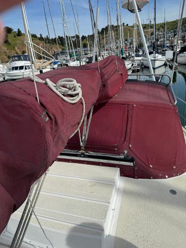 1984 Endeavour 38 sailboat with maroon covers docked in a marina.