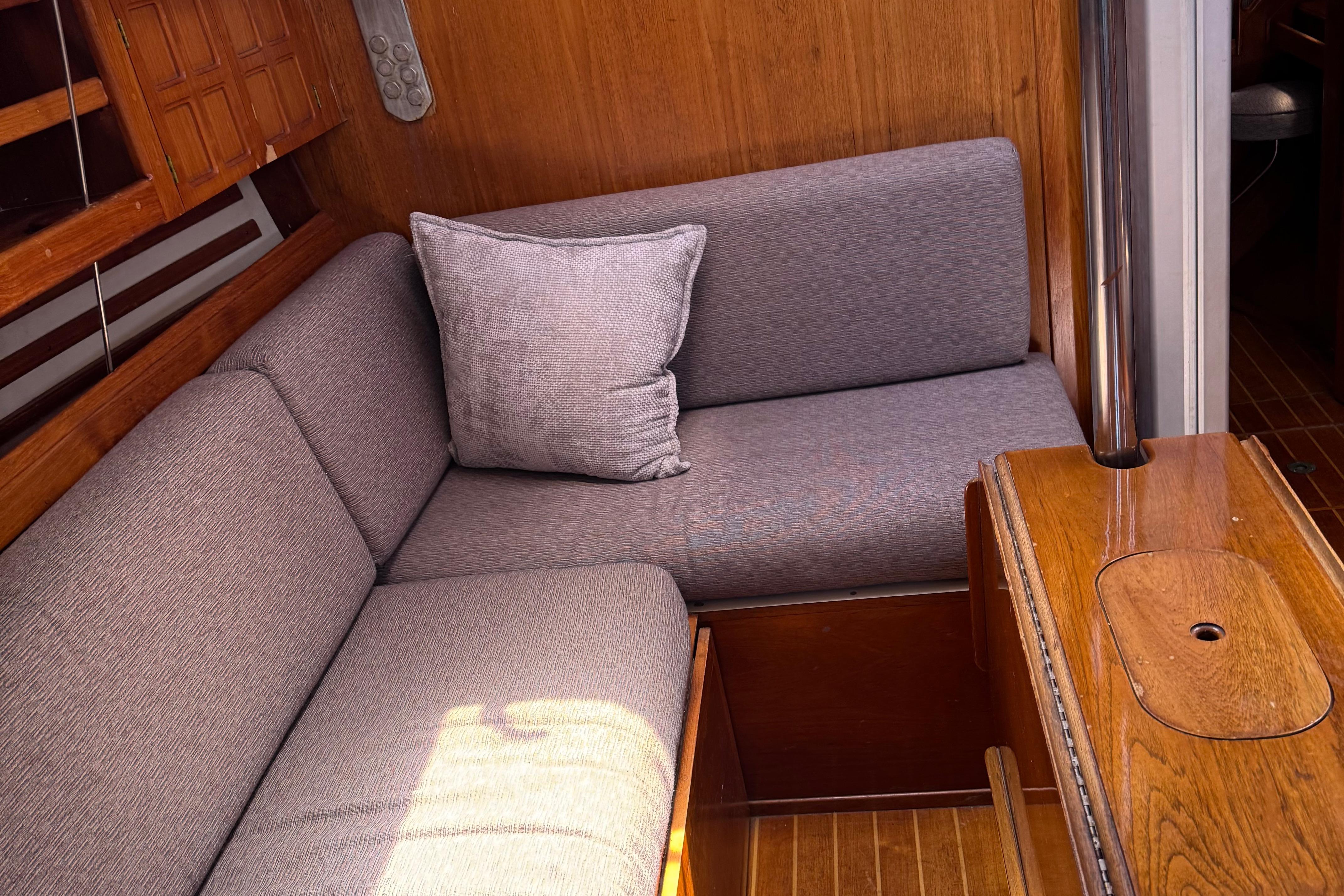 Cozy interior of 1984 Endeavour 38 sailboat with cushioned seating and wooden accents.