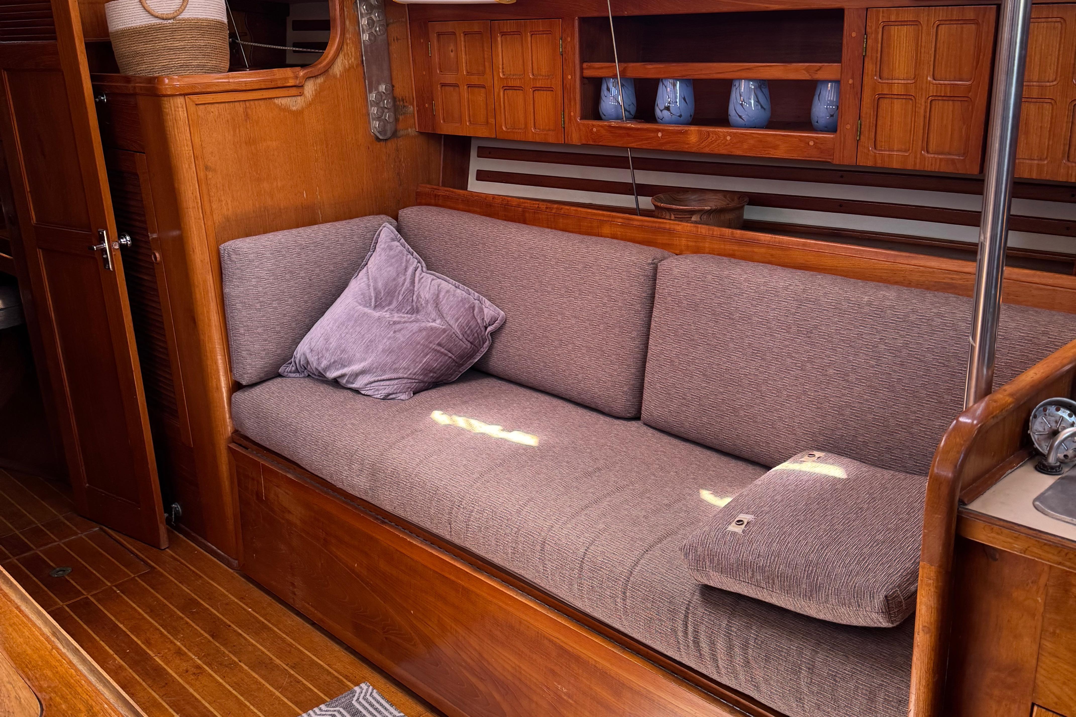 Cozy interior of 1984 Endeavour 38 sailboat with cushioned seating and wooden cabinetry.