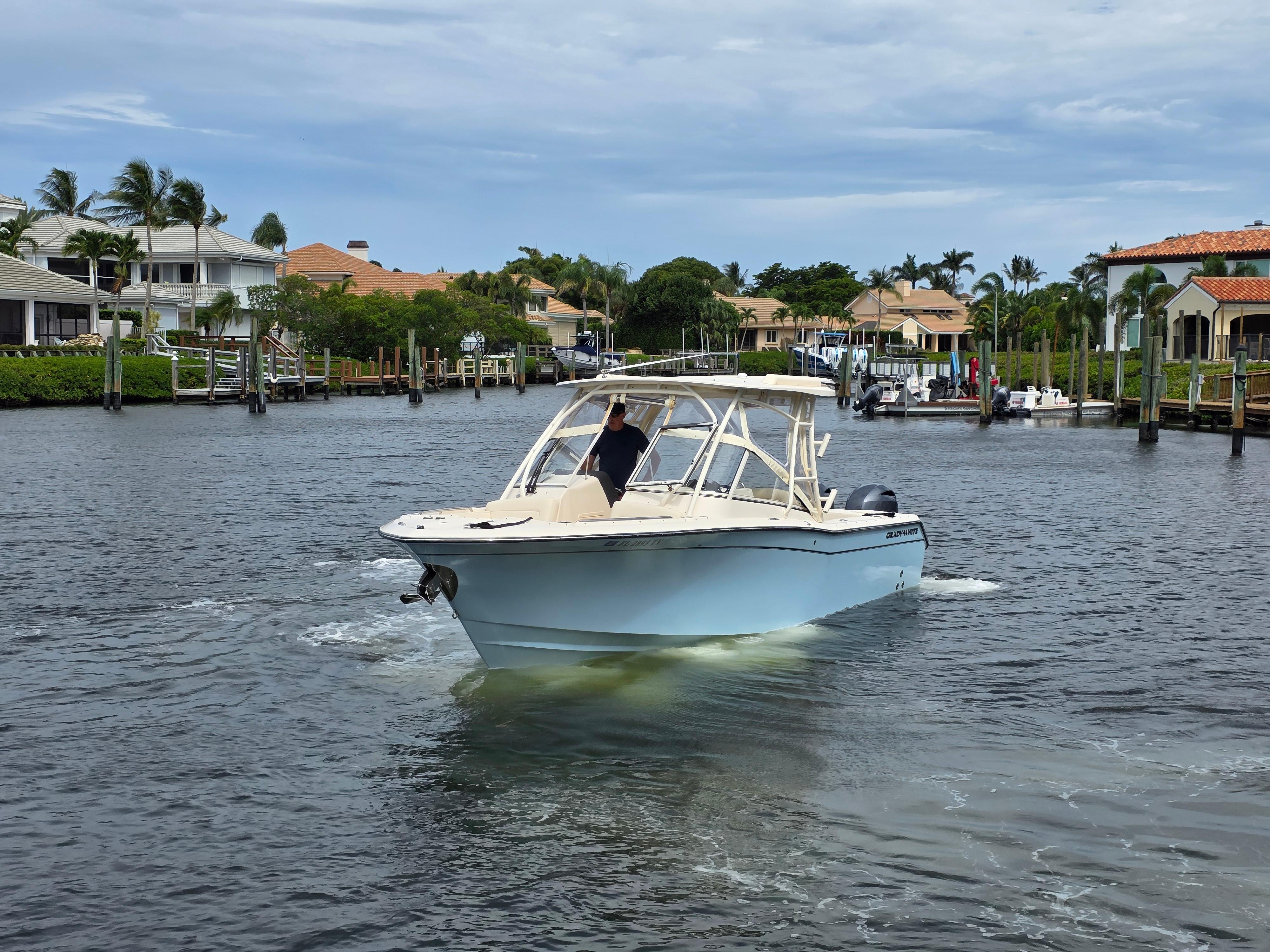 2023 Grady-White Freedom 275 boat cruising in a scenic waterfront neighborhood.