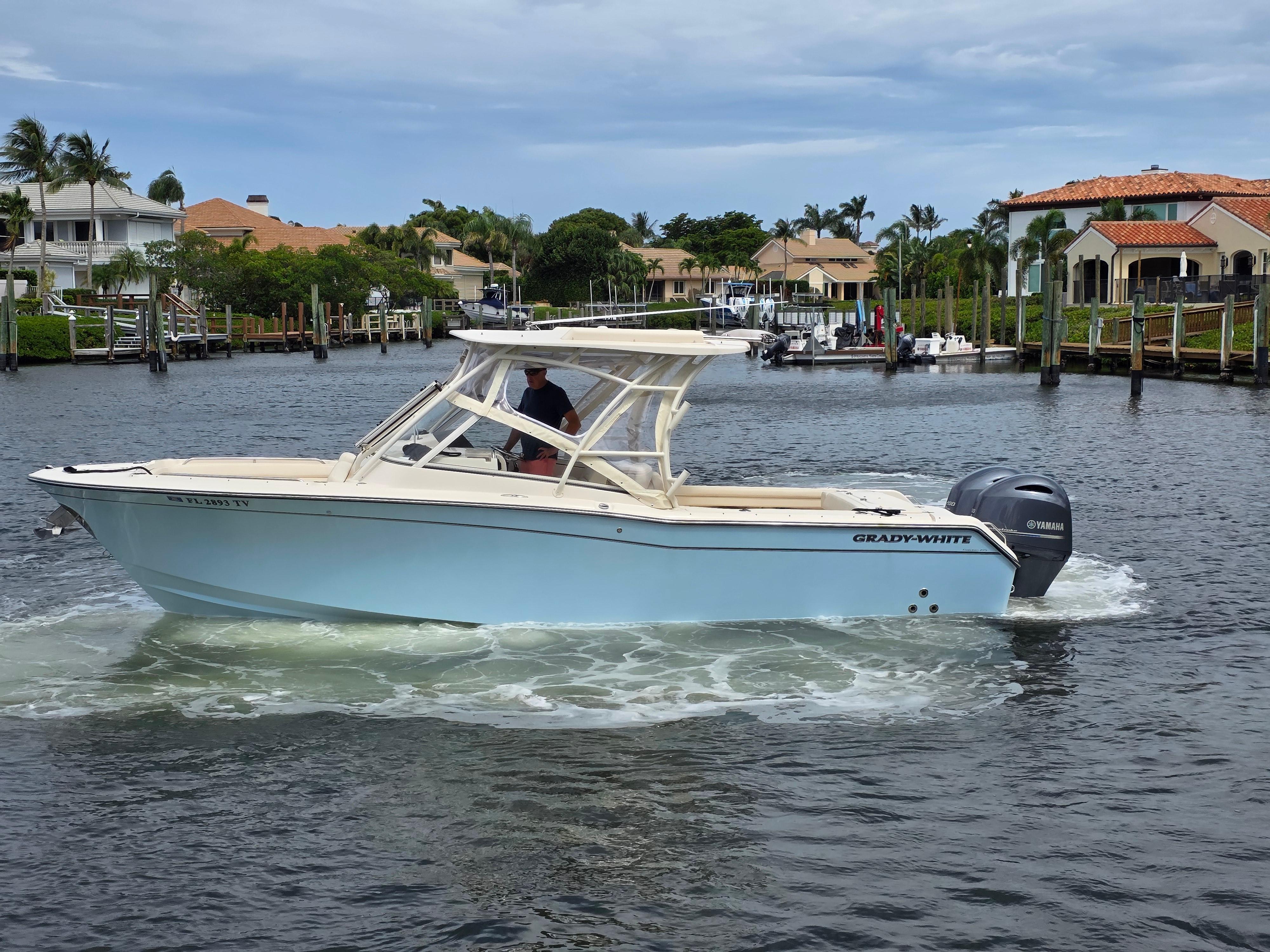 2023 Grady-White Freedom 275 boat cruising in a scenic waterfront neighborhood.