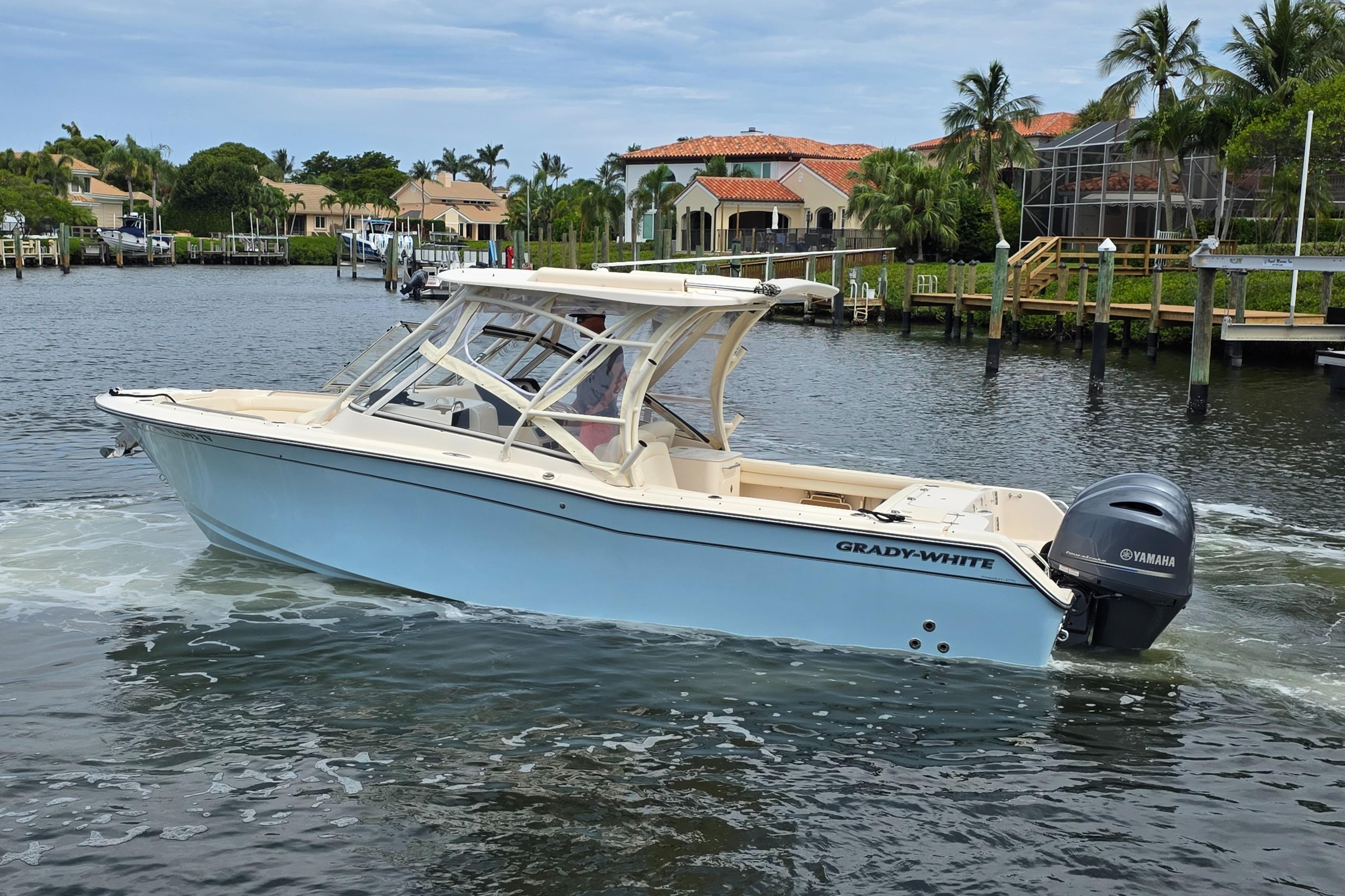 2023 Grady-White Freedom 275 boat cruising on a scenic waterway with waterfront homes.