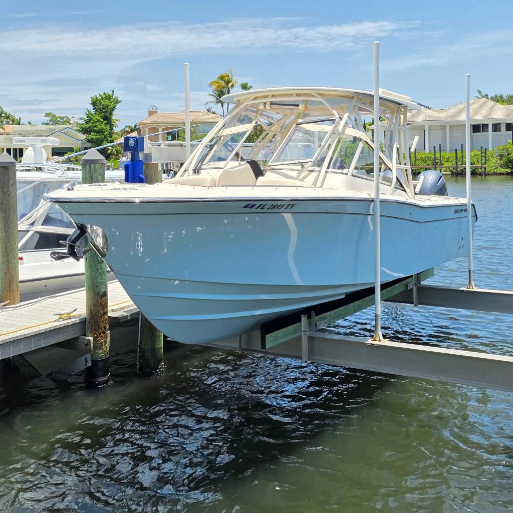 2023 Grady-White Freedom 275 boat docked on a lift in a sunny marina.