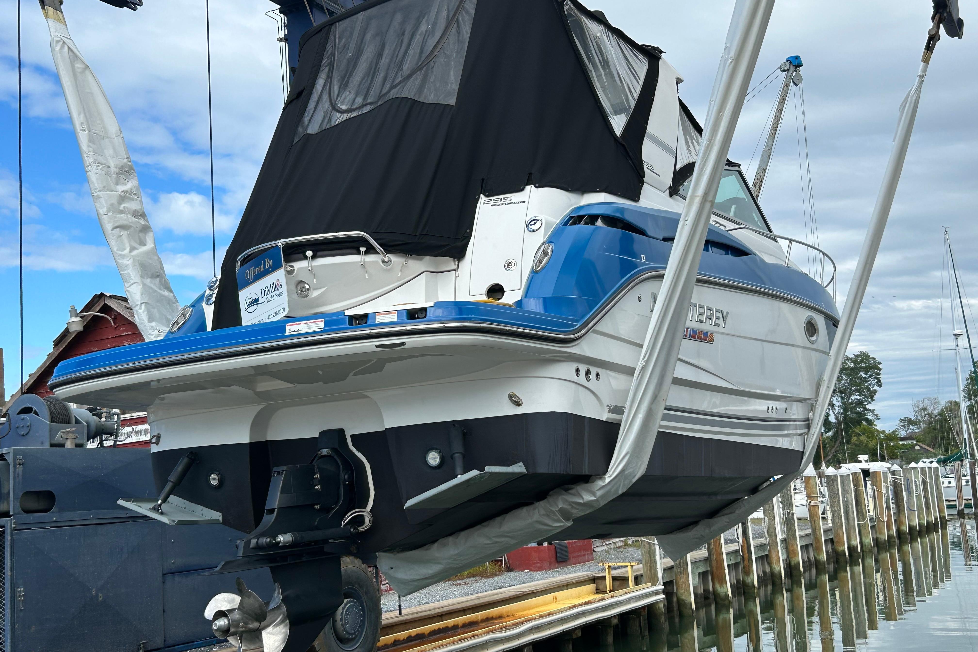 2019 Monterey 295 Sport Yacht lifted at marina, showcasing sleek design and blue accents.