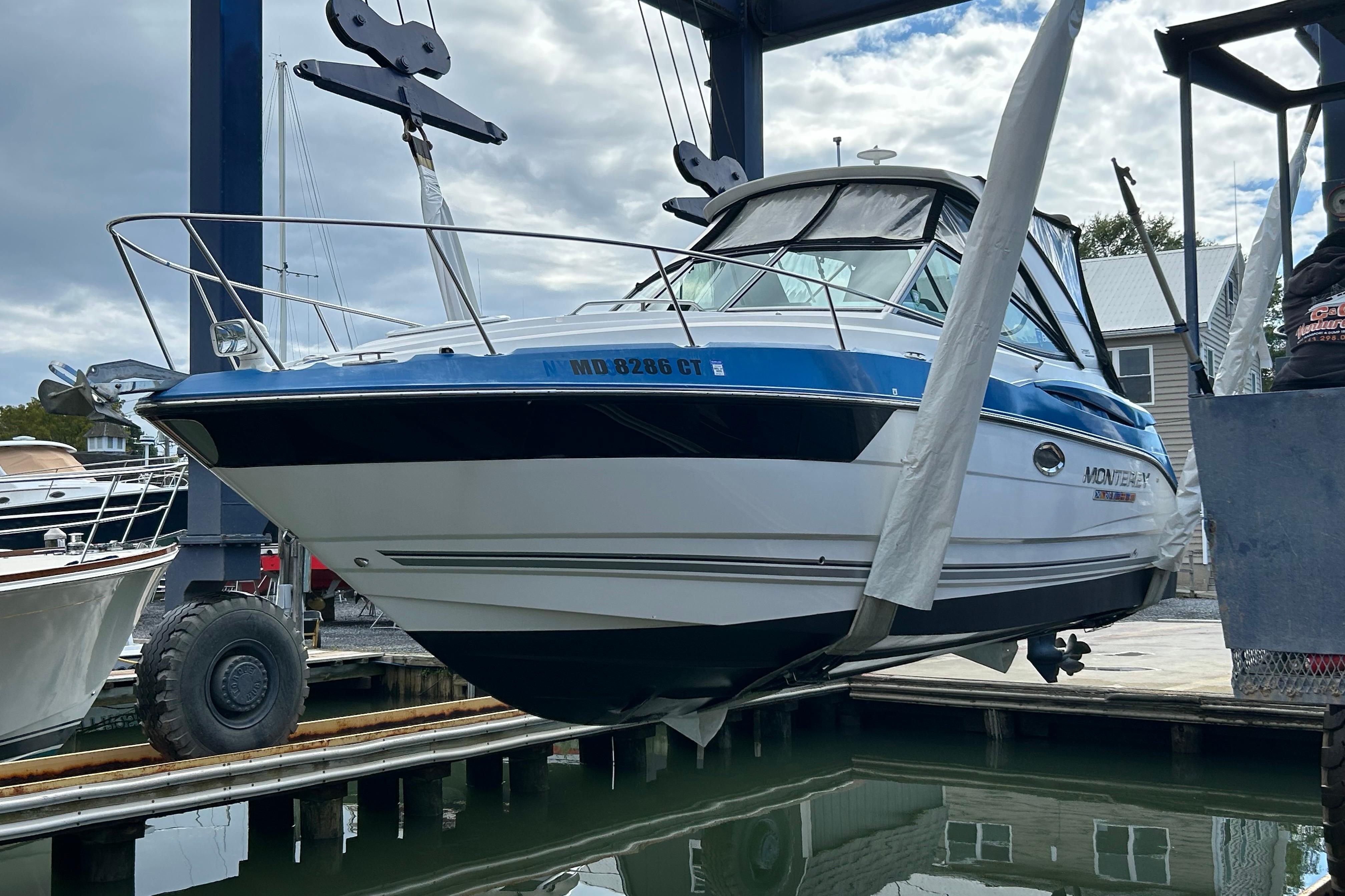 2019 Monterey 295 Sport Yacht in dry dock, blue and white hull, marina background.
